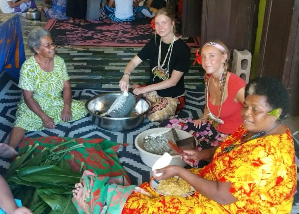 A cultural experience with Fijian woman showing guests how to prepare traditional food sitting on floor together
