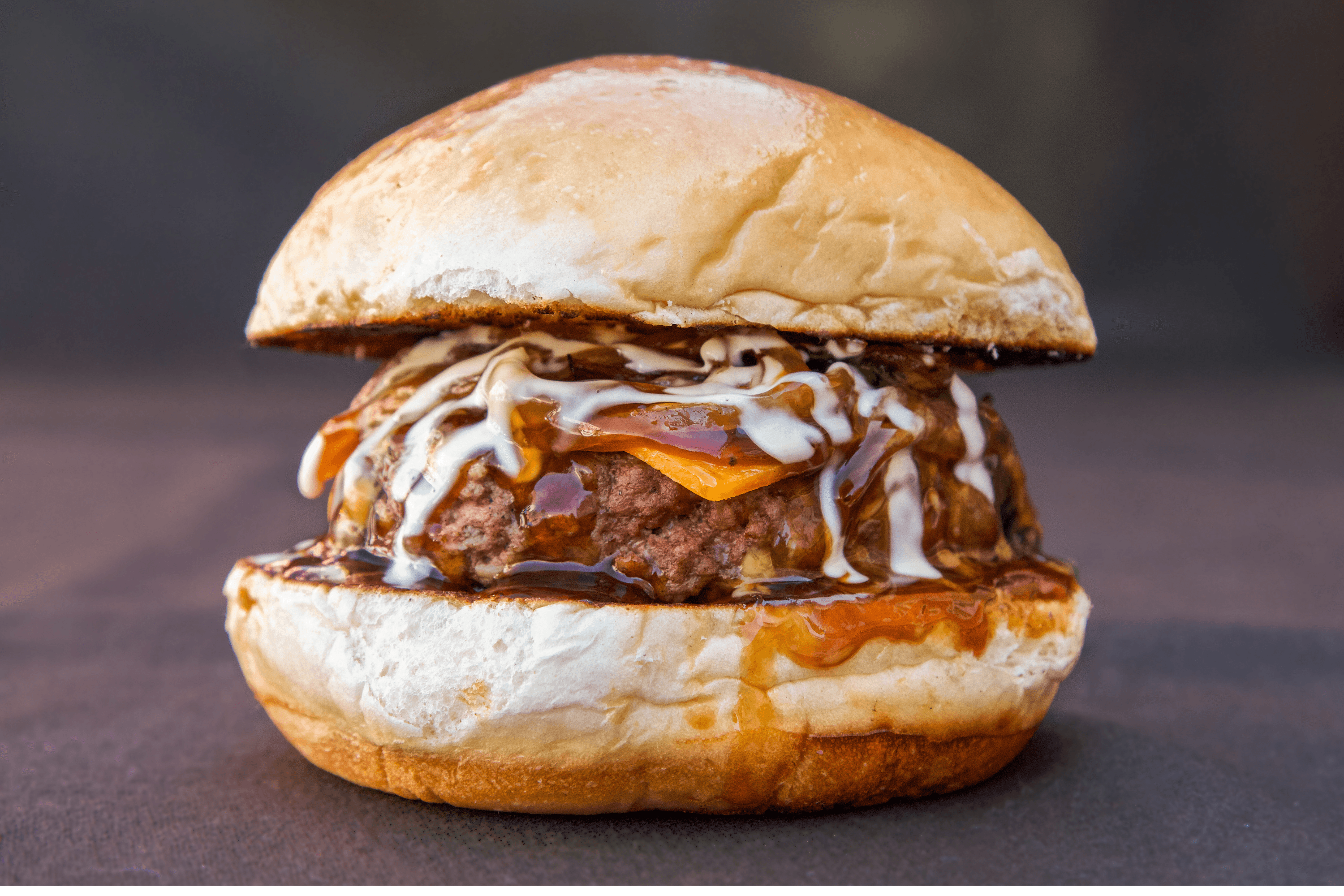 An overhead, rustic photo of a wooden table covered with food, featuring a round pizza cut into quarters, a bowl of French fries, a dish of white cheese slices, and several glasses of water.
