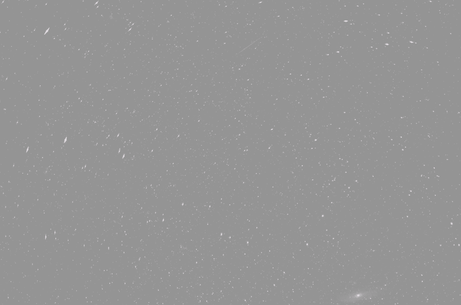 Sternenklarer Nachthimmel mit zahlreichen hellen Sternen, die über einen dunklen Hintergrund verstreut sind. In der unteren rechten Ecke ist eine kleine, schwache Galaxie sichtbar.