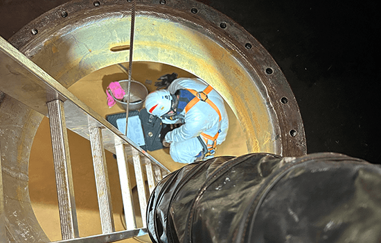 Four diverse professionals collaboratively working on a laptop, with one person pointing at the screen while others observe.