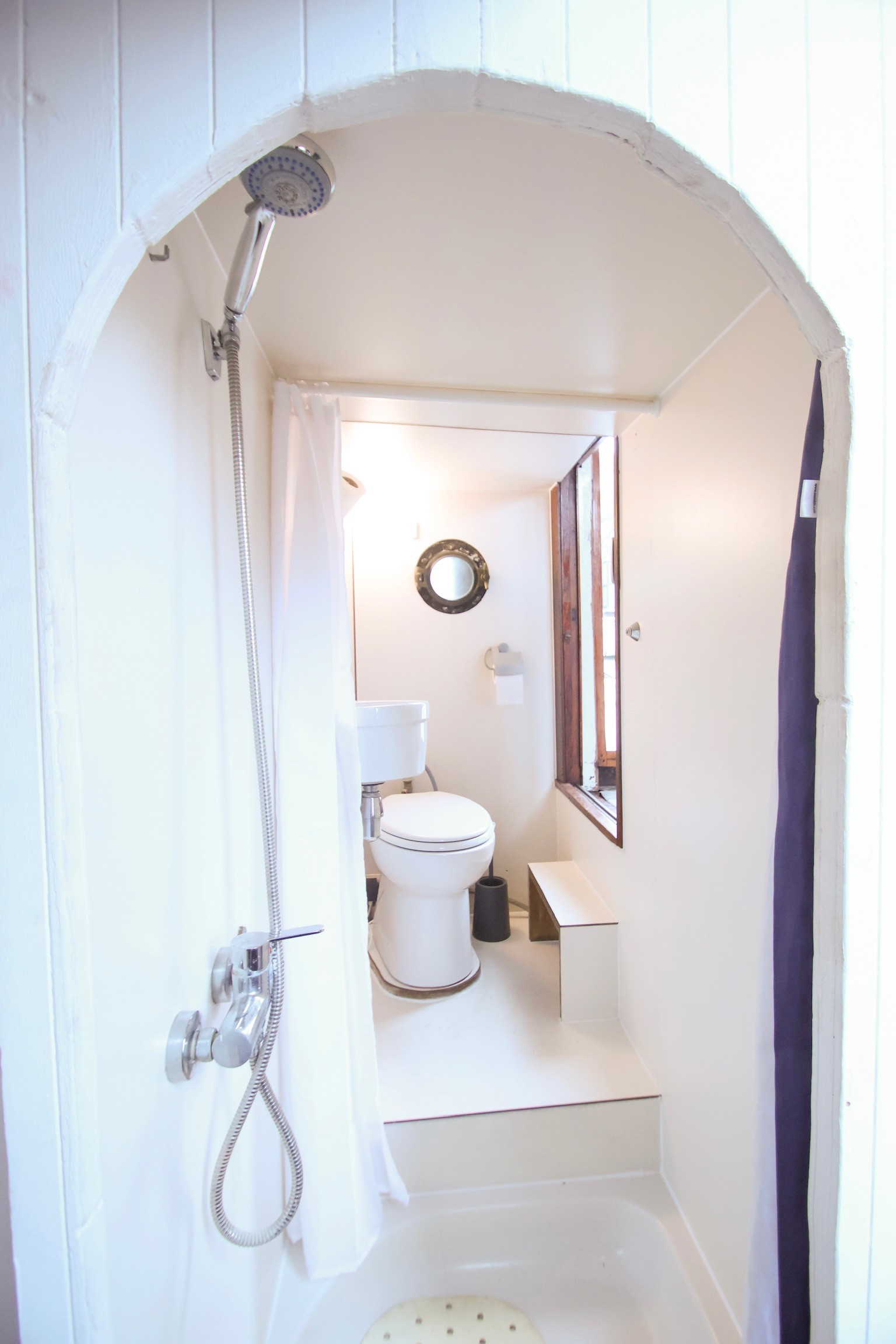 Beige upholstered bed with patterned pillows and ottomans