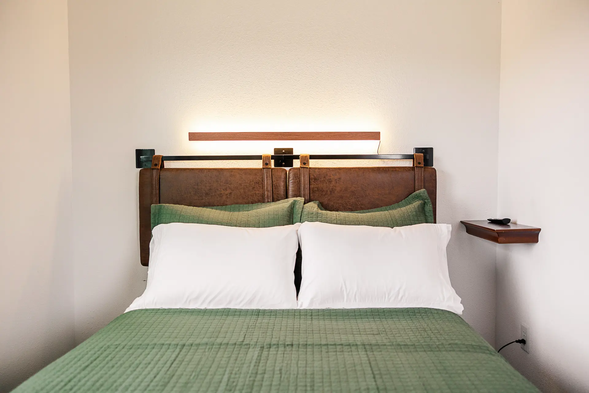Double bed with green quilt and leather headboard at Trophy Lodge.