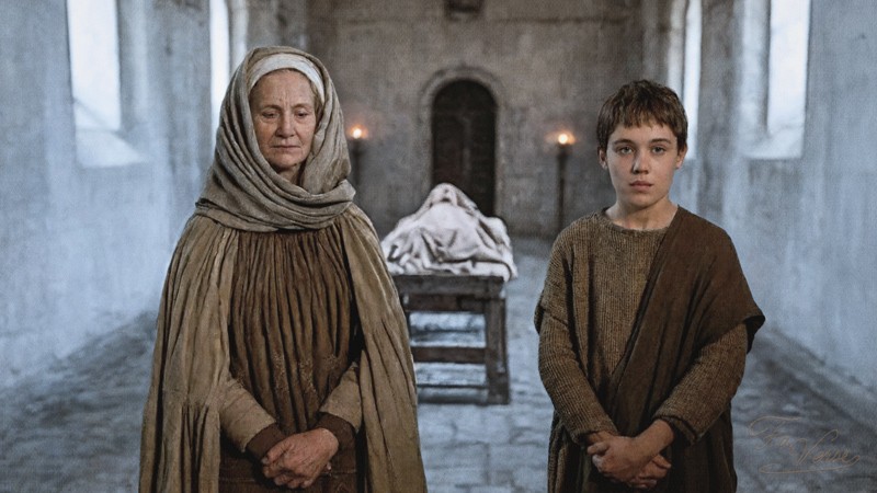 Sacred artwork by Faith and Verse. © Faith and Verse, 2025. All rights reserved. Saint Ludmila of Bohemia, veiled in red, sits beside the young Wenceslaus as he reads from a scroll in a quiet medieval courtyard—a moment of instruction and legacy beneath a budding spring tree and weathered stone wall.