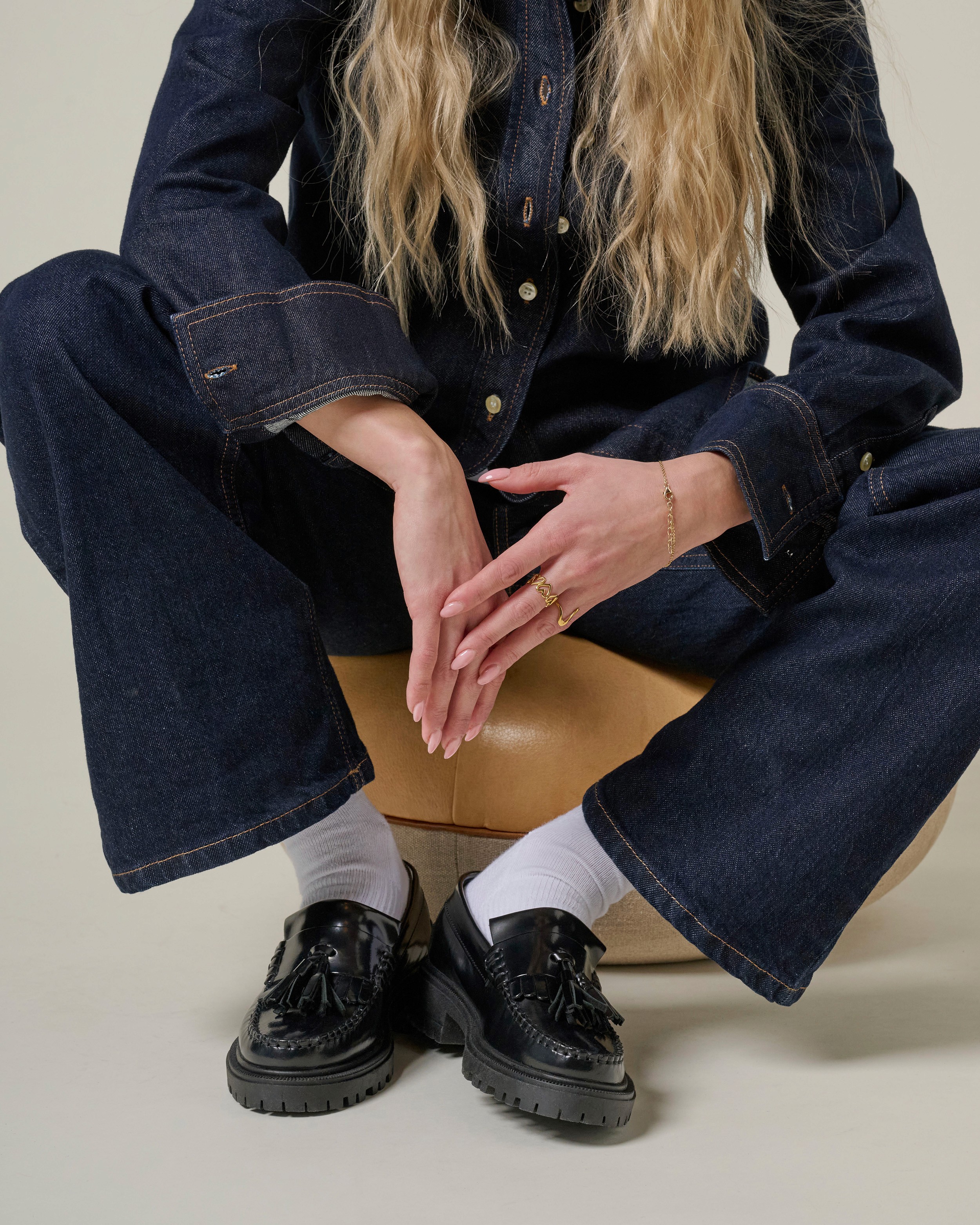 Le bas de la silhouette d'une femme, oprtant du denim et des mocassins noirs à grosses semelles