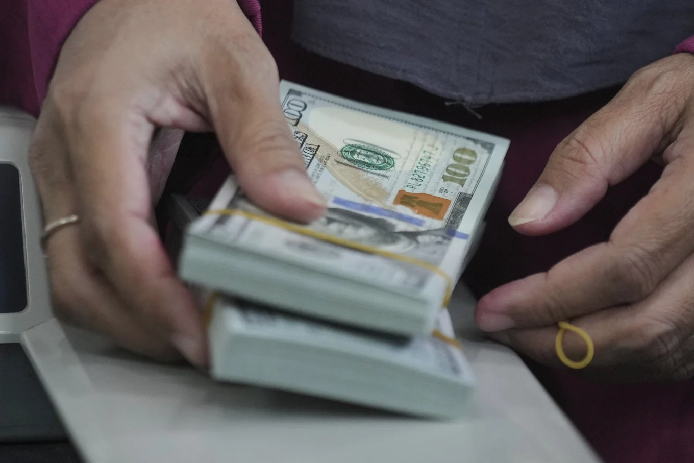 An employee holds U.S. dollar notes at a money changer in Jakarta, Indonesia, Thursday, Aug. 7, 2025. (AP Photo/Tatan Syuflana)