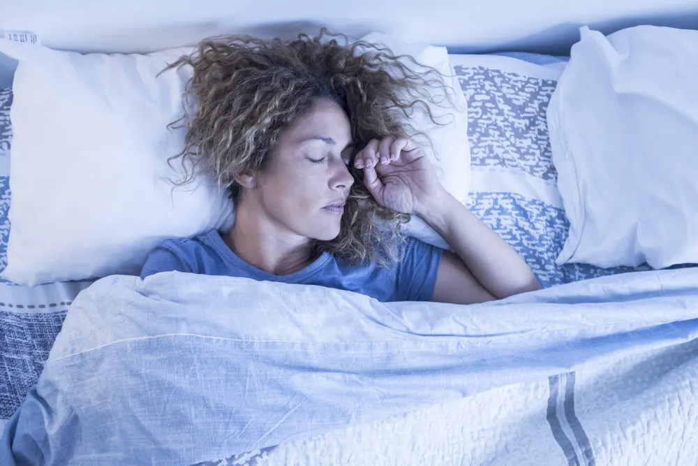 oman sleeping peacefully in bed, covered with a blue-and-white patterned blanket.