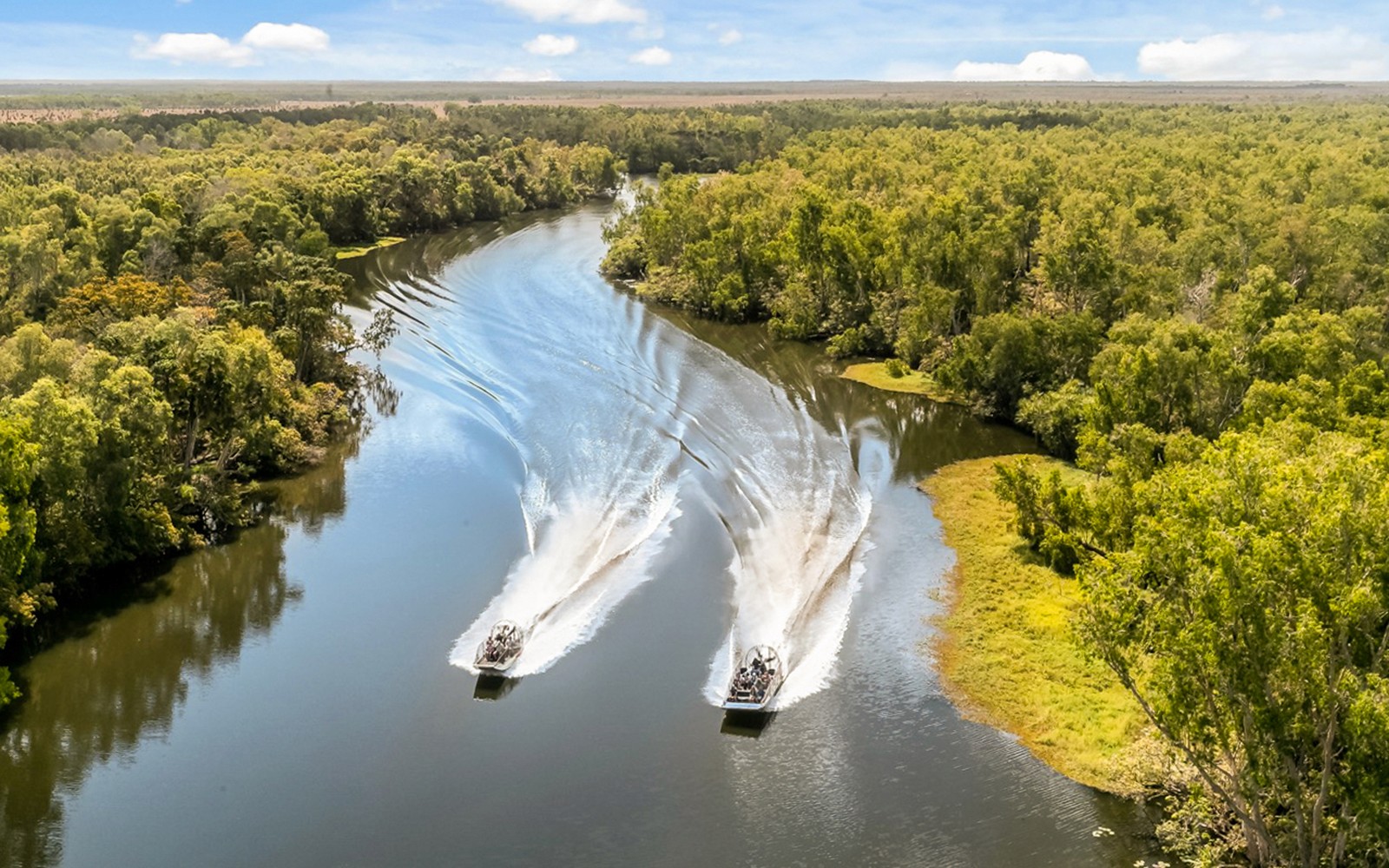 Airboats cruising along the Finniss River surrounded by lush greenery.