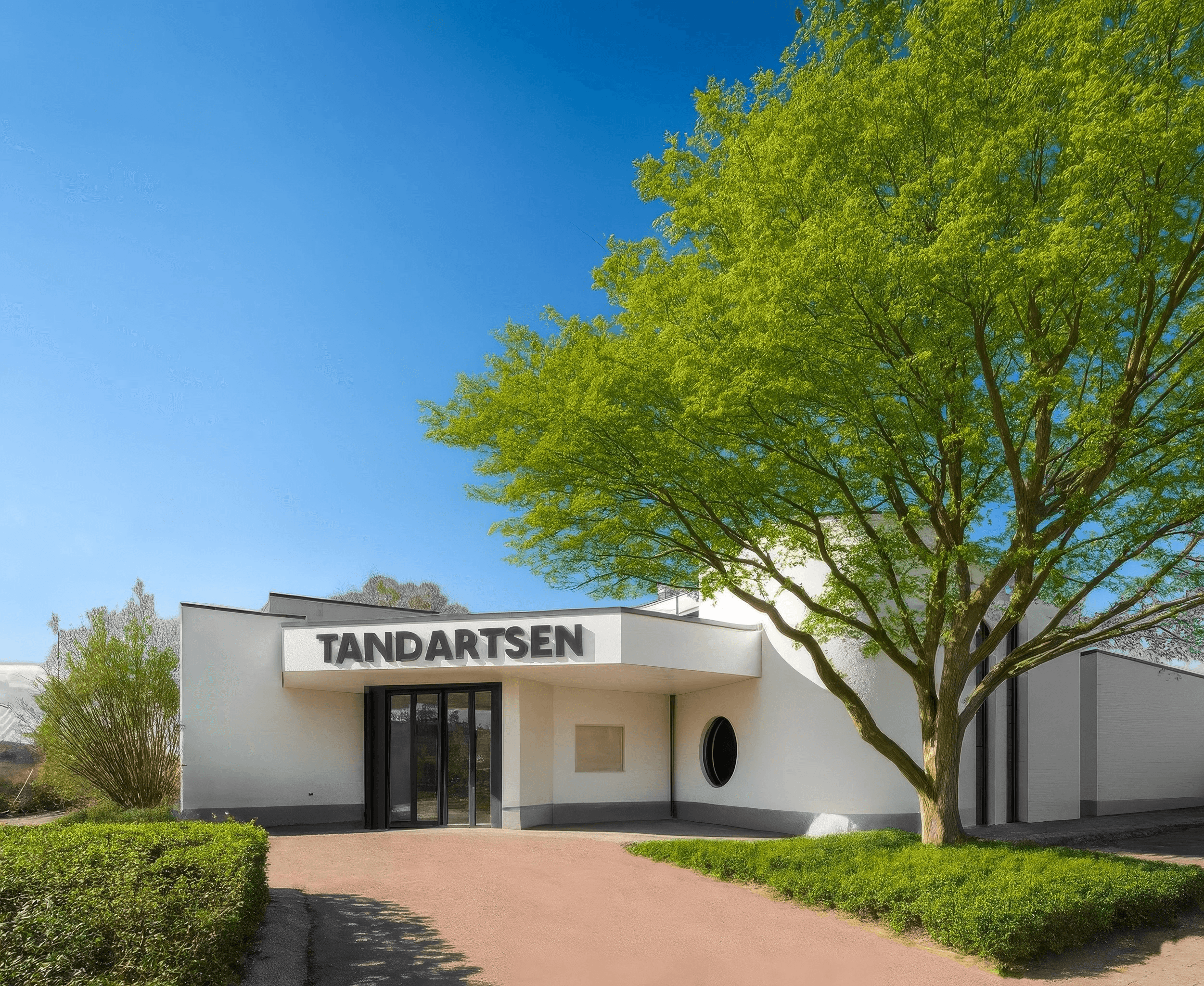 Modern building with large windows, surrounded by greenery and a clear blue sky. Pathway leading to the entrance.