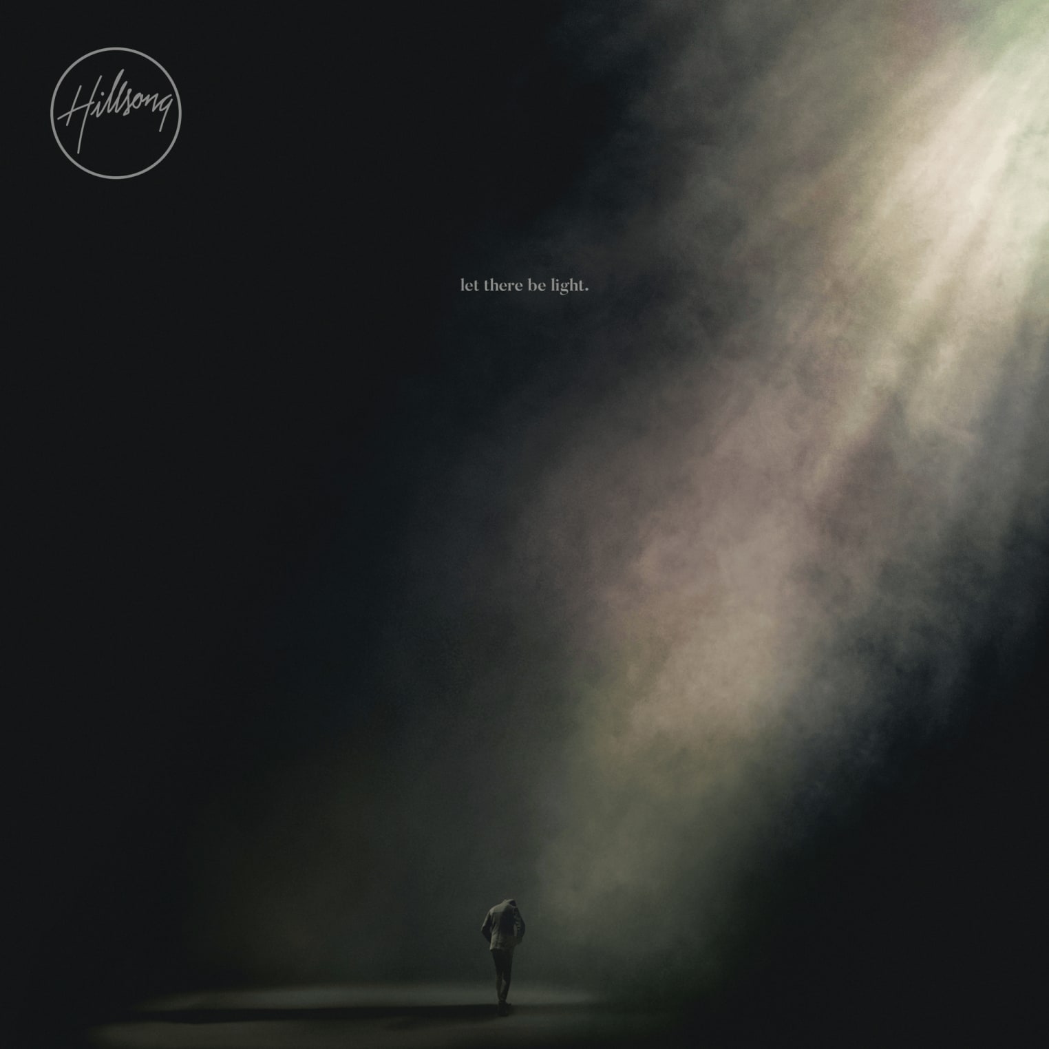 Album artwork for "What A Beautiful Name" by Hillsong Worship: a lone figure in darkness, lit by a beam; text reads "let there be light." and Hillsong.