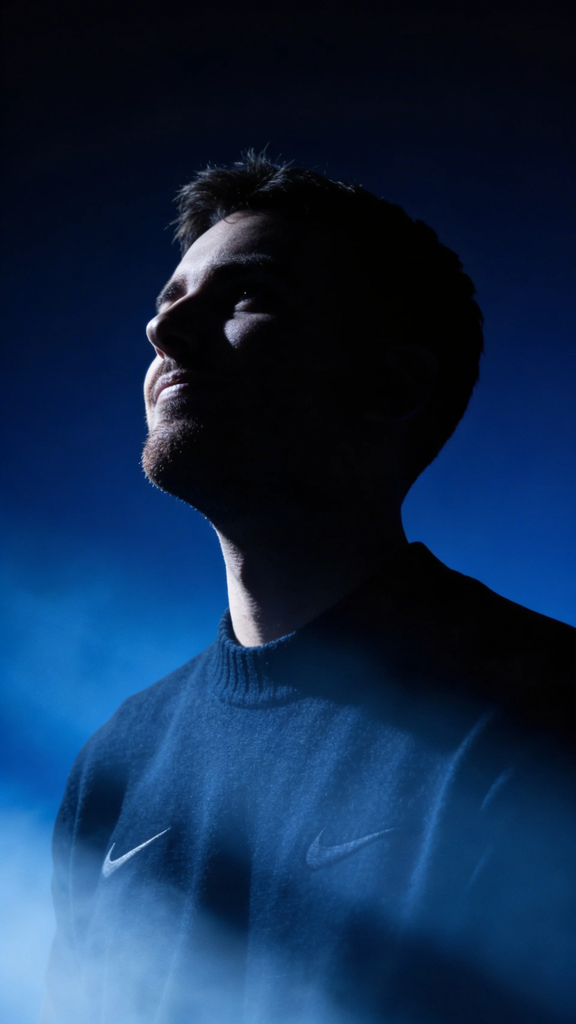 A thoughtful young person with dark hair gazes to the side, captured in soft black and white lighting.