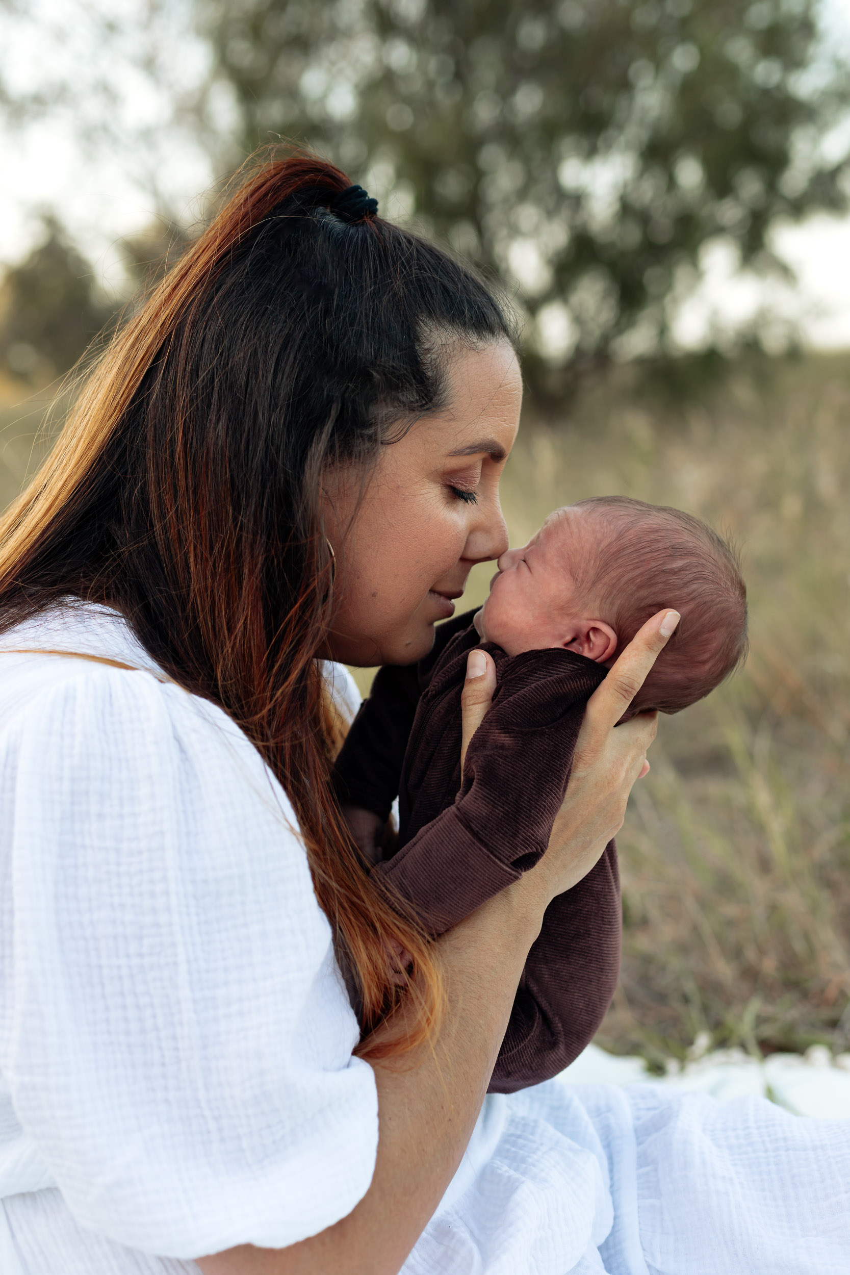 Mother touching nose with newborn baby