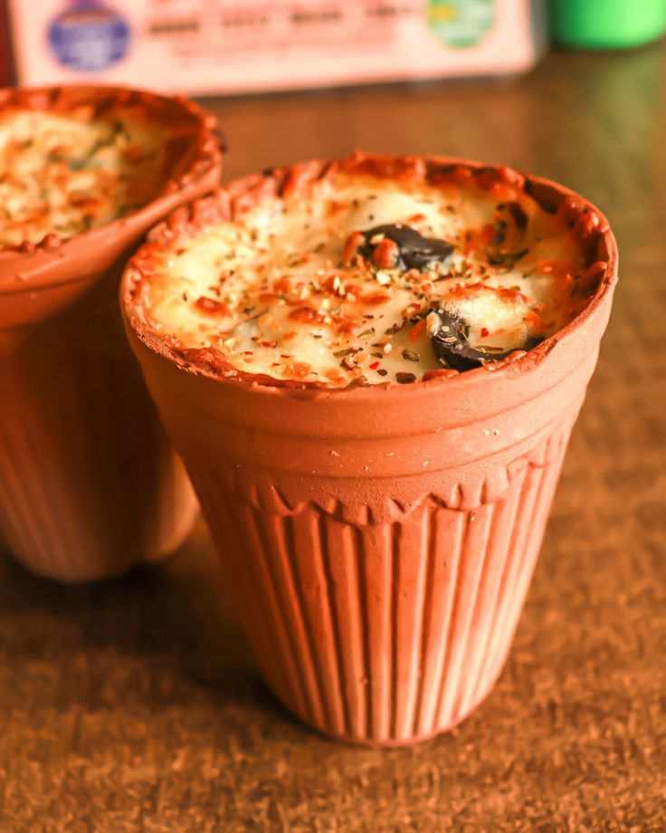 Two plates of pasta topped with herbs, crushed nuts, and a drizzle of sauce, set on a wooden table.