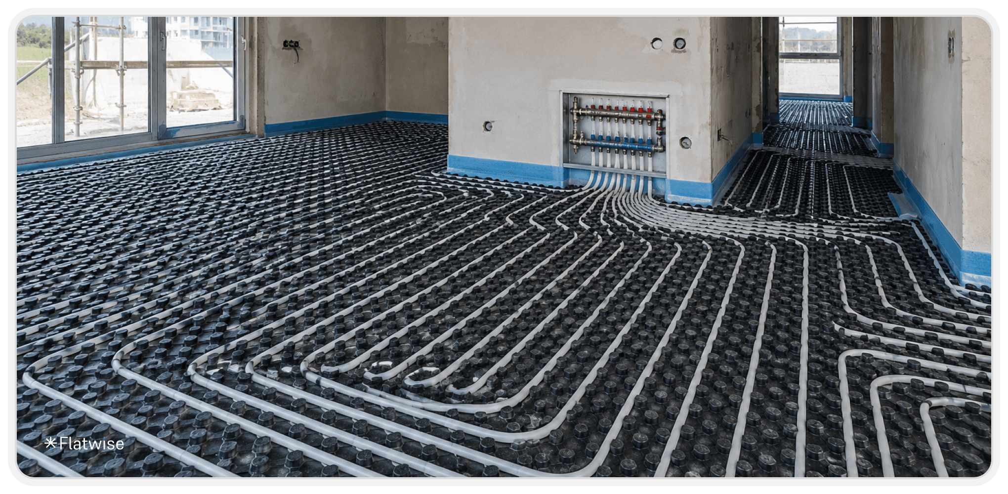 Eine im Bau befindliche Wohnung mit installierter Fußbodenheizung. Weiße Heizungsrohre verlaufen in gleichmäßigen Schleifen über schwarzen Noppenplatten am Boden. Im Hintergrund sind unverputzte Wände, große Fenster mit Tageslicht sowie ein Heizkreisverteiler sichtbar. Das Bild ist im Landscape-Format aufgenommen und vermittelt eine moderne Neubau- oder Sanierungssituation.
