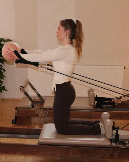 Frau liegt auf dem Reformer und hebt ein Bein senkrecht in die Luft – Reformer Pilates Übung im REFORMHER STUDIO Dresden