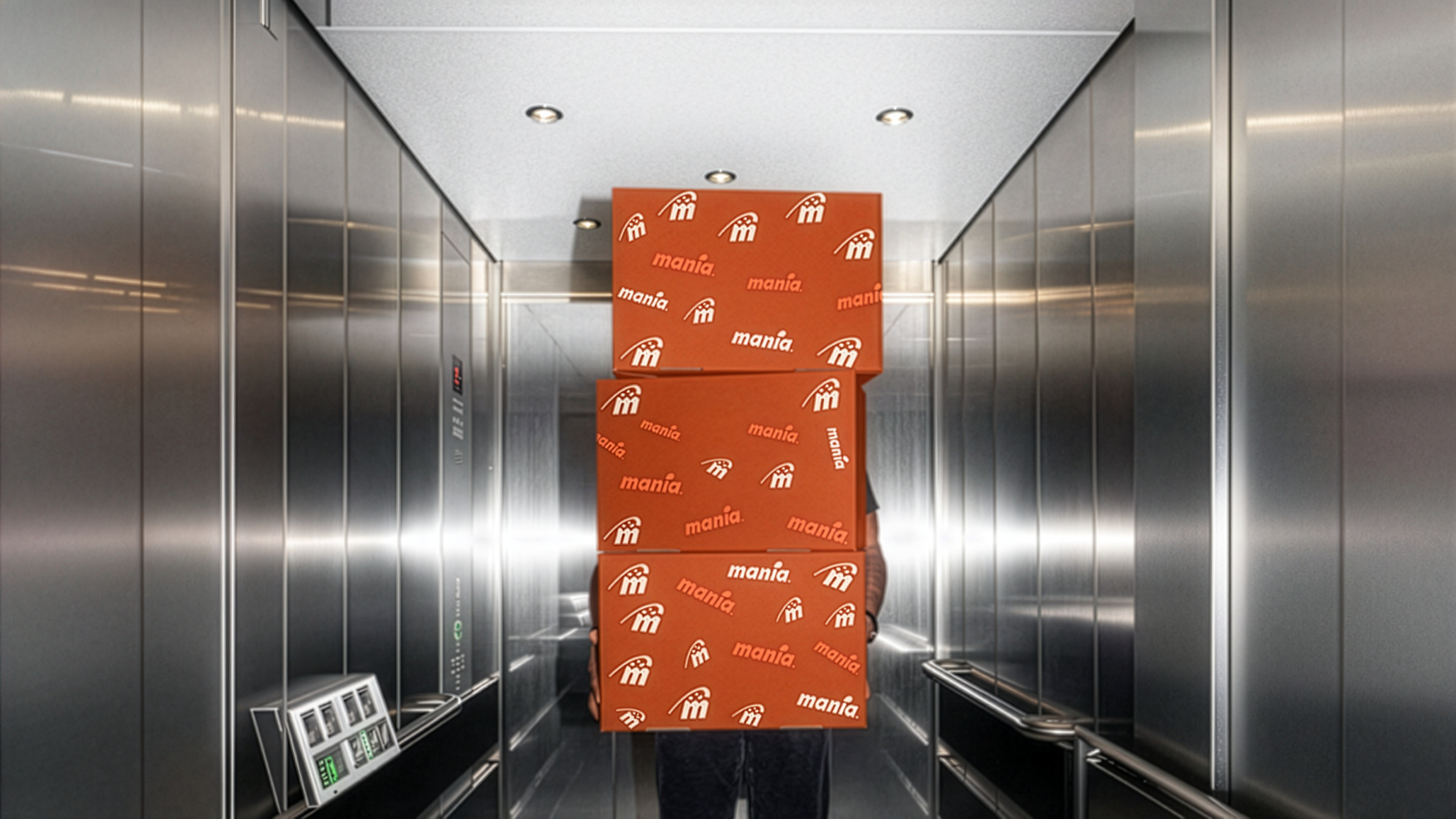 Deep orange boxes with coral logos all over/ 3 boxes and man carries them in metallic elevator. 