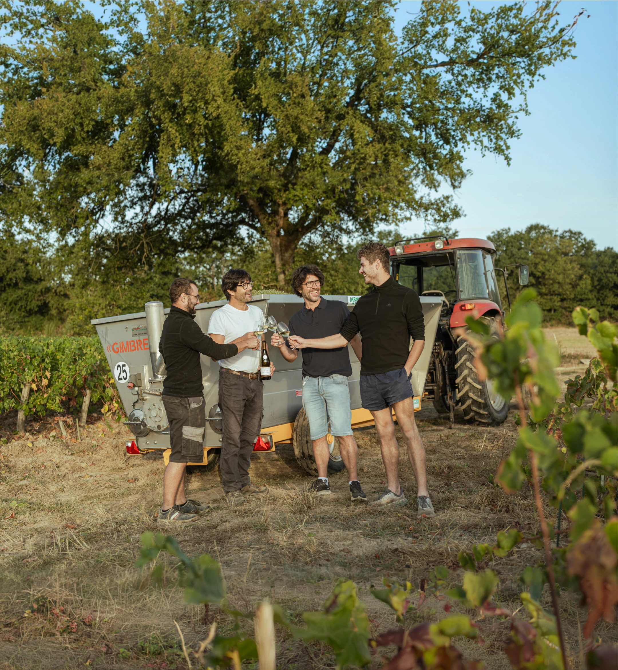 L'équipe du domaine trinquant devant un tracteur dans les vignes