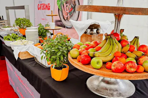 A vibrant table setting featuring burgers, hot dogs, fries, and colorful drinks, illuminated by string lights.