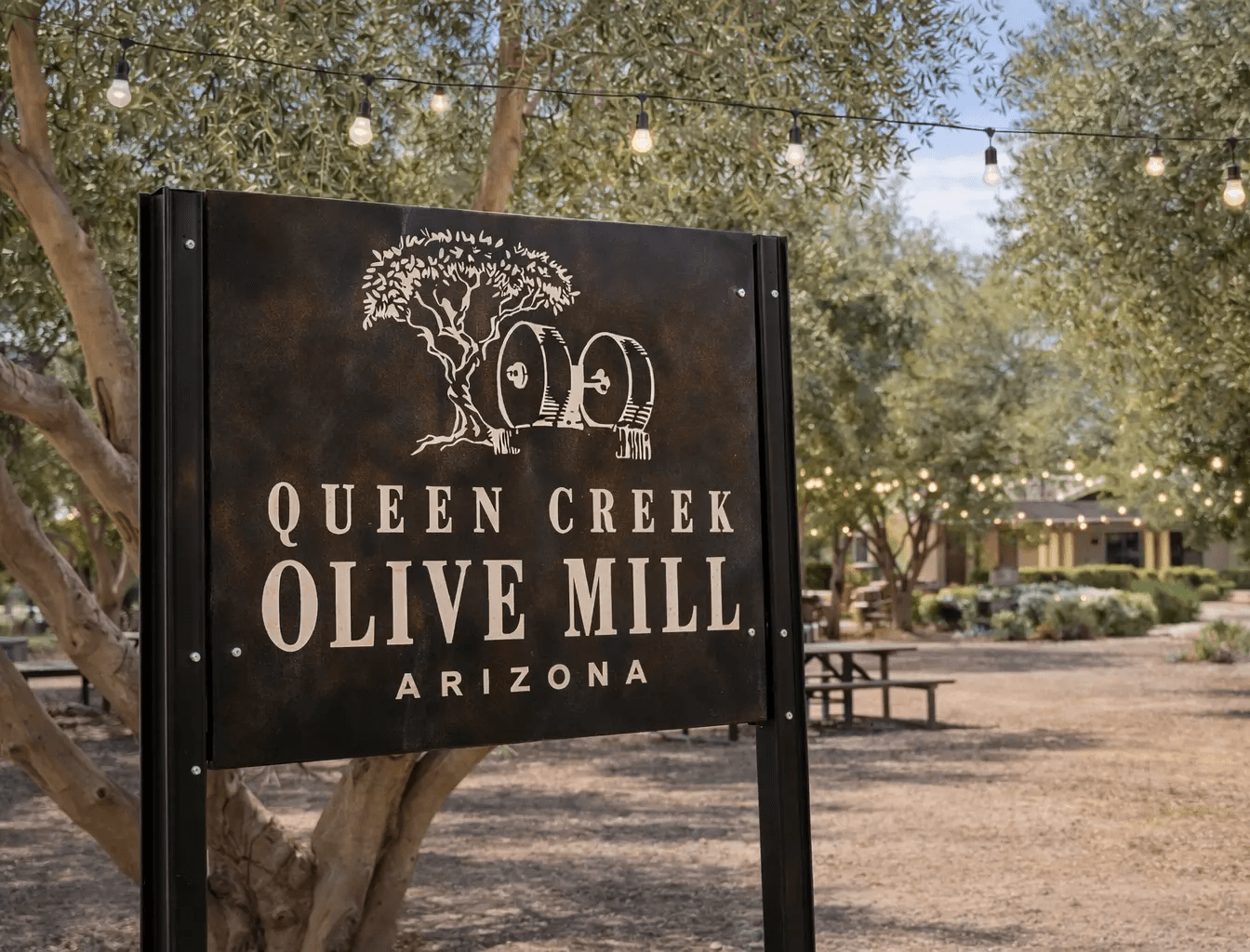 The rustic metal entrance sign for the Queen Creek Olive Mill, a central landmark for our house cleaning services in Queen Creek.