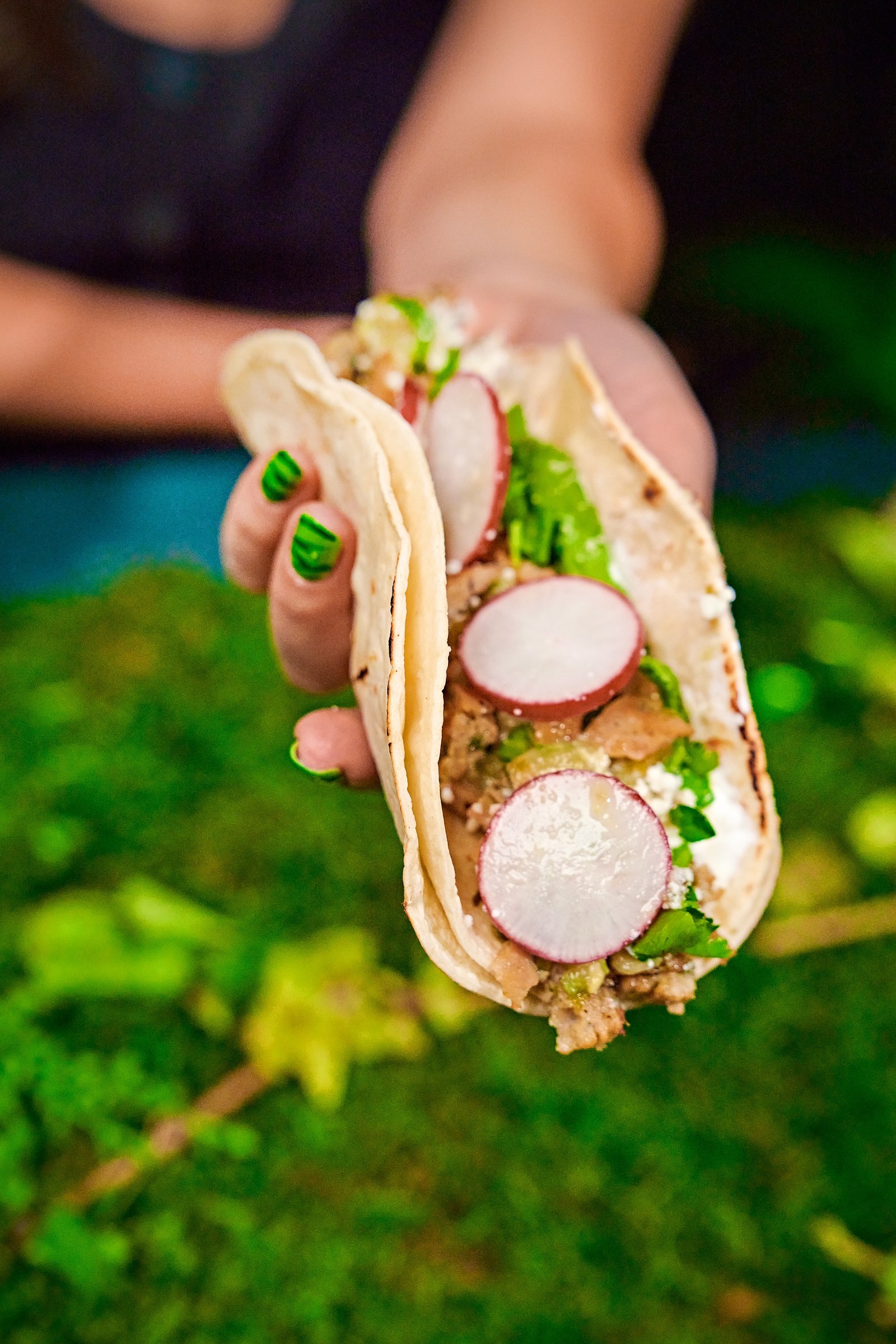 Cut-open Salsa Verde sausage sandwich held in hand