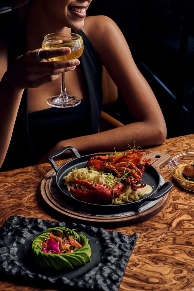 A guest enjoying lobster pasta and a premium cocktail at Dhoom, highlighting Toronto’s evolving Indian fine dining scene with upscale, contemporary flavours.