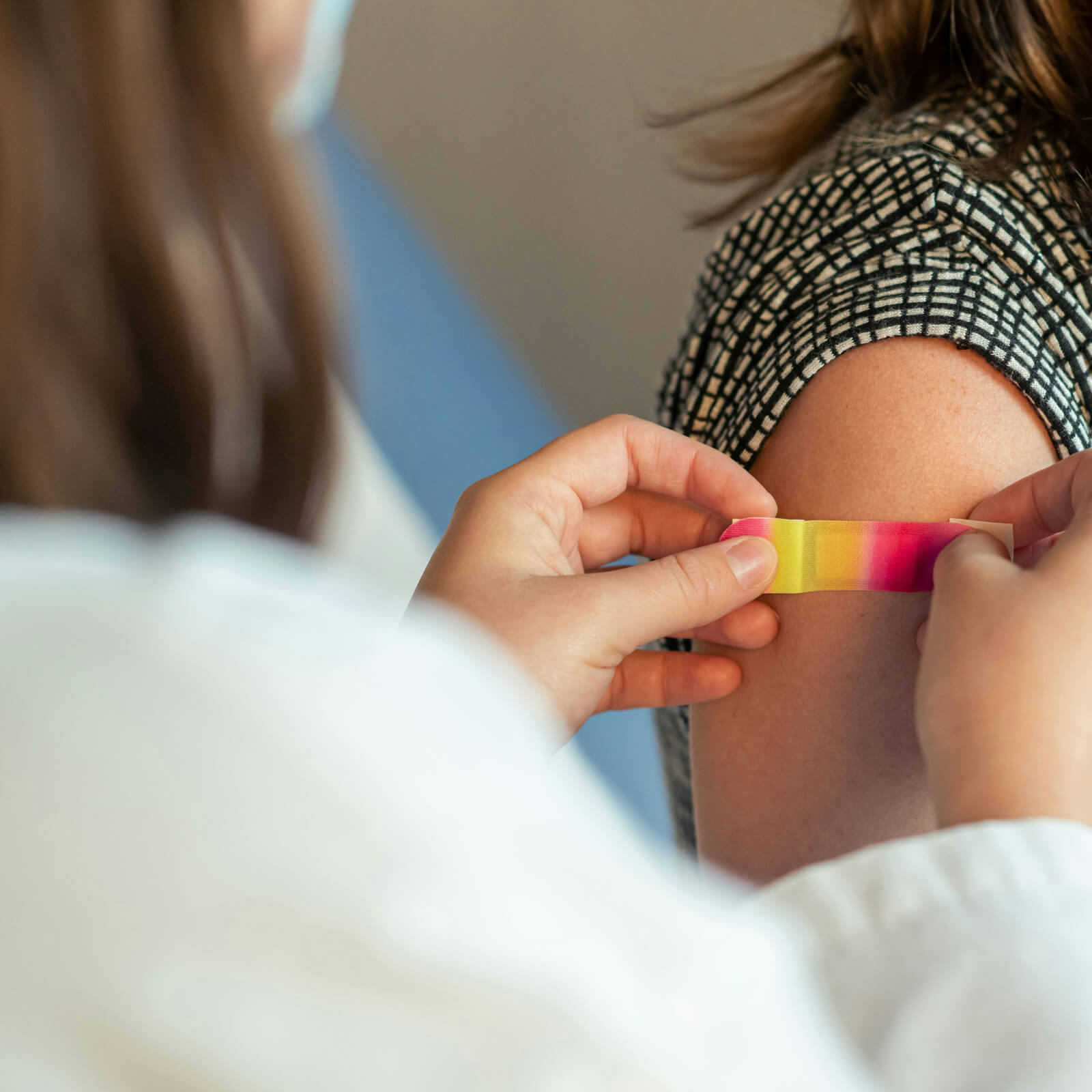 Eine Patientin bekommt ein Pflaster an den Oberarm von der Ärztin