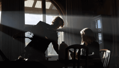 Connor Jansen filming a dim lit scene inside a rustic home with Maggie Game