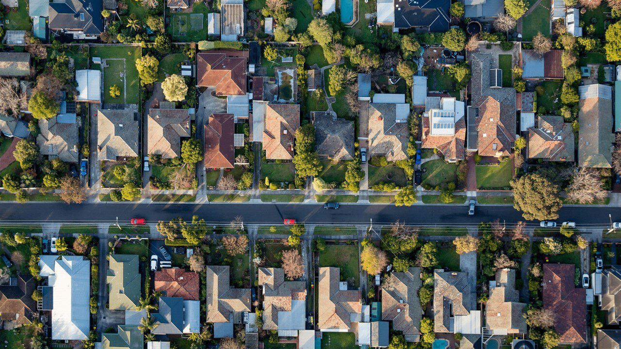 Aerial view of suburban houses and street with cars.