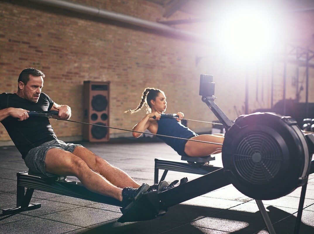 couple using the best machine at the gym for weight loss while doing rowing exercises
