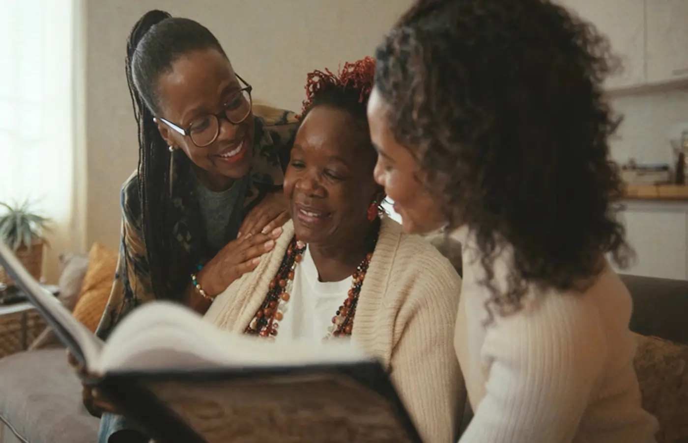 Senior client looking through a book with caregivers at home — supporting daily conversation and speech practice