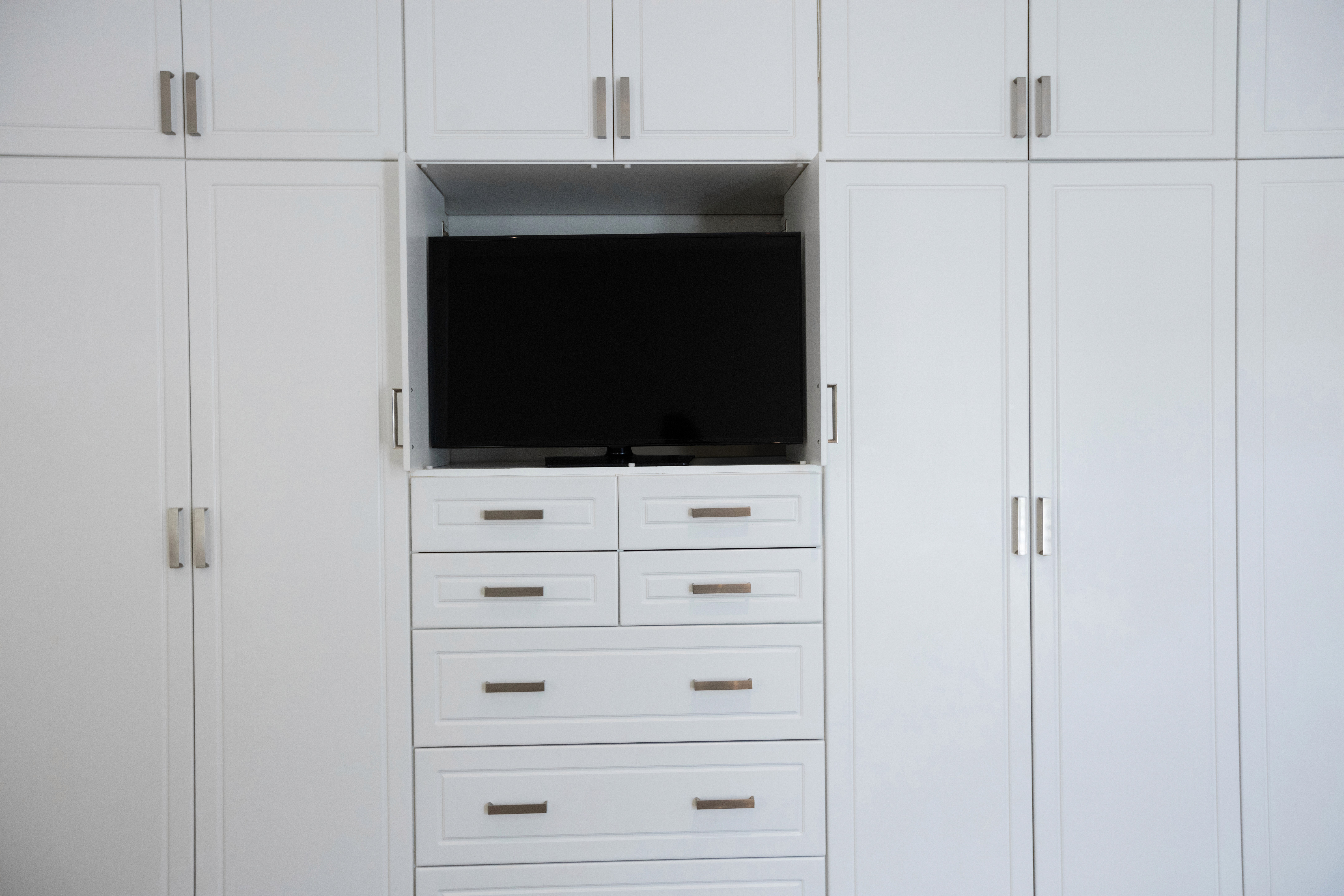 A white big storage cabinet with doors and shelves. 