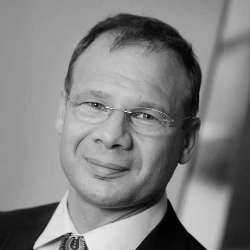 Black and white picture of a man with glasses and suit looking at the camera