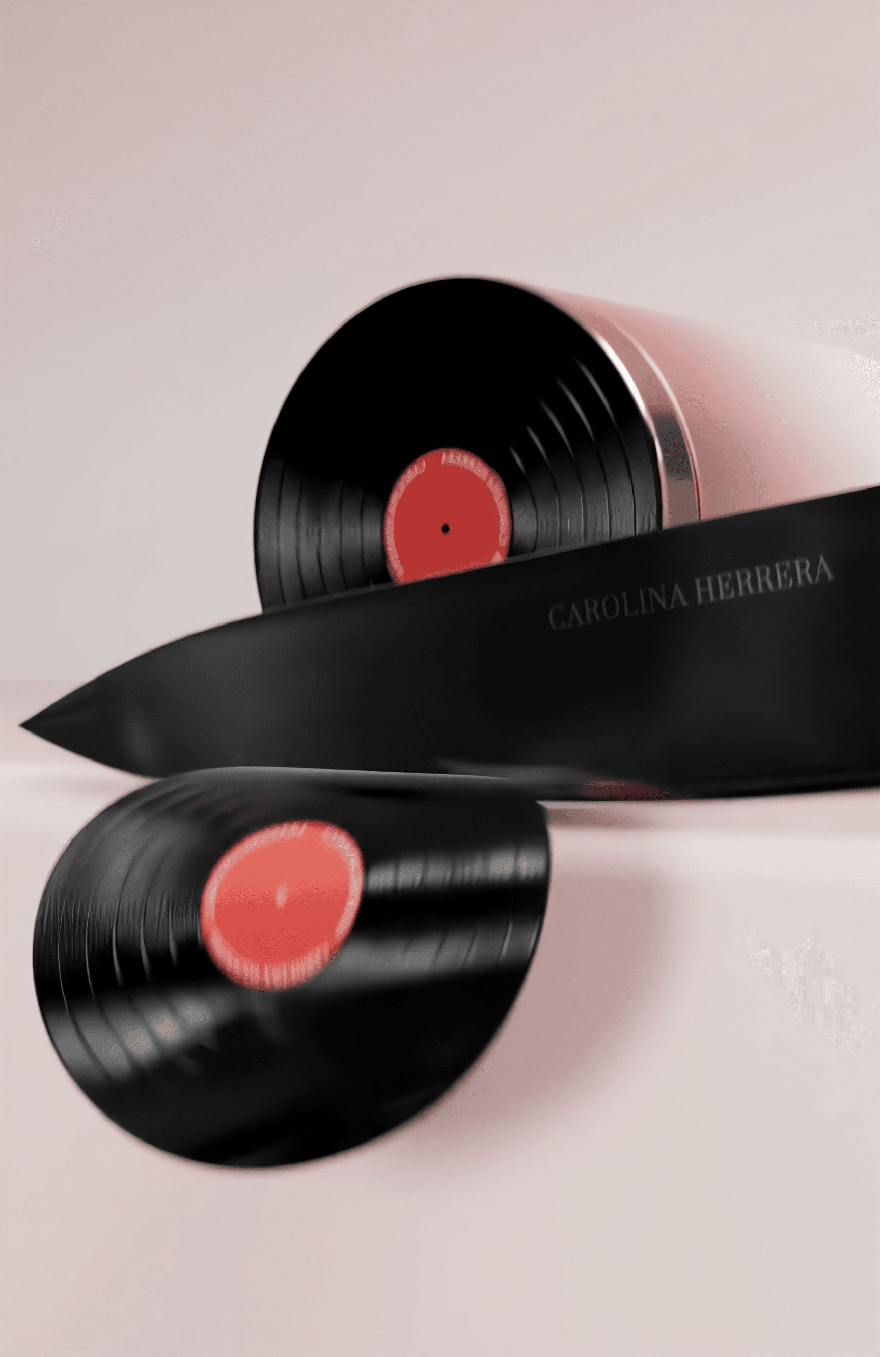 A surreal 3D render shows a black kitchen knife slicing through a Carolina Herrera branded record