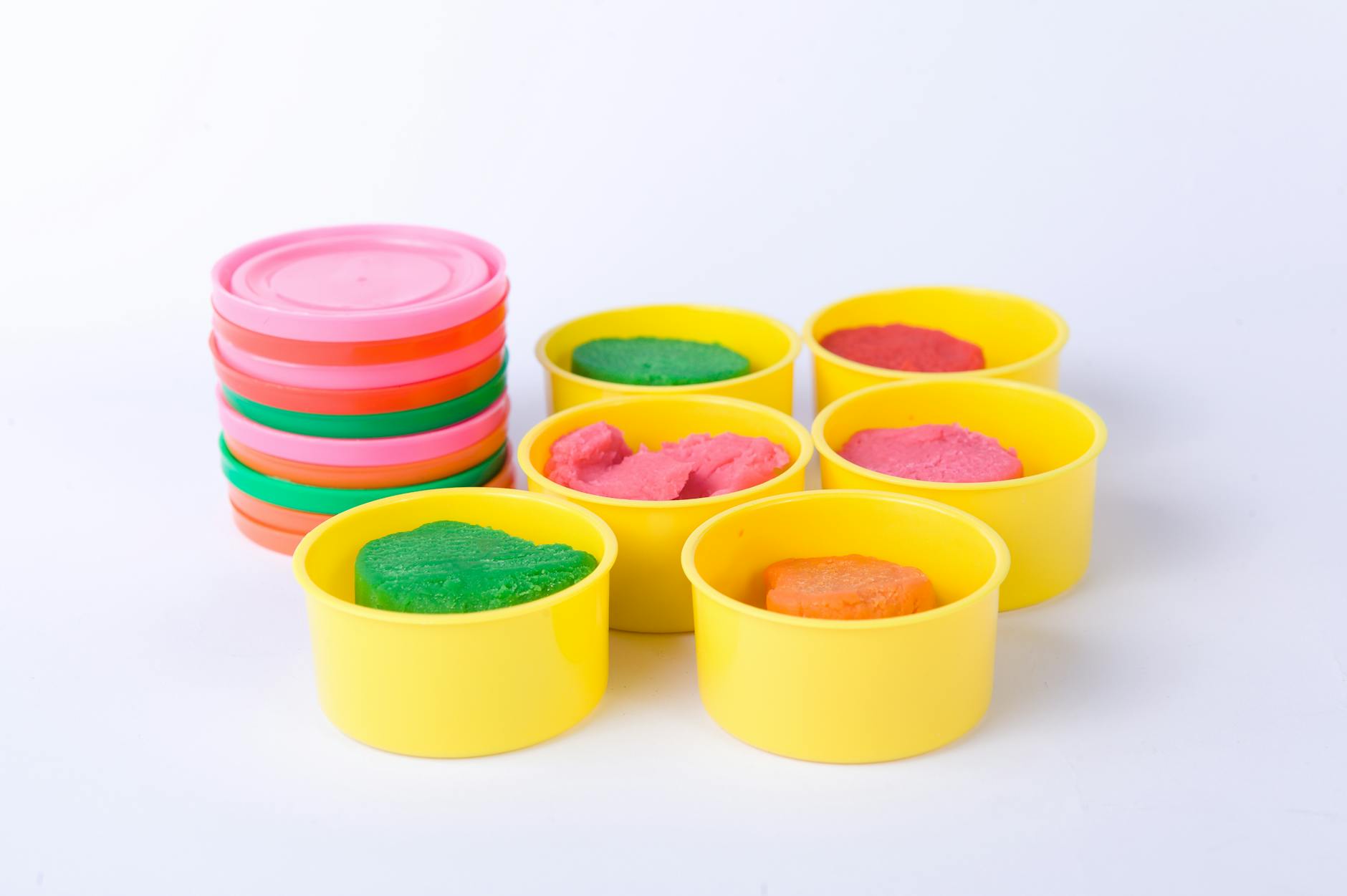 Primary students using tweezers to move colorful pom-poms into sorting trays at a fine motor station.