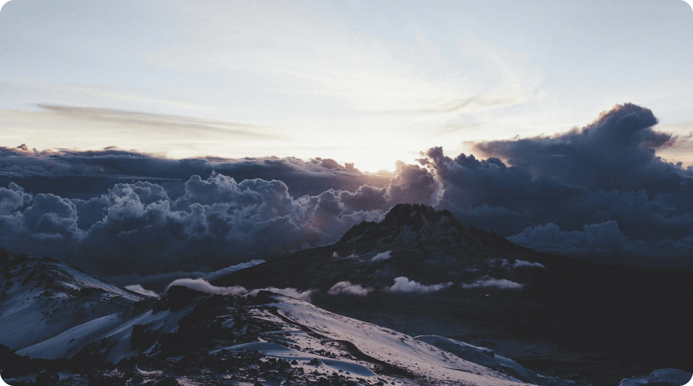 A serene landscape at sunrise, with mountains silhouetted against a brightening sky.
