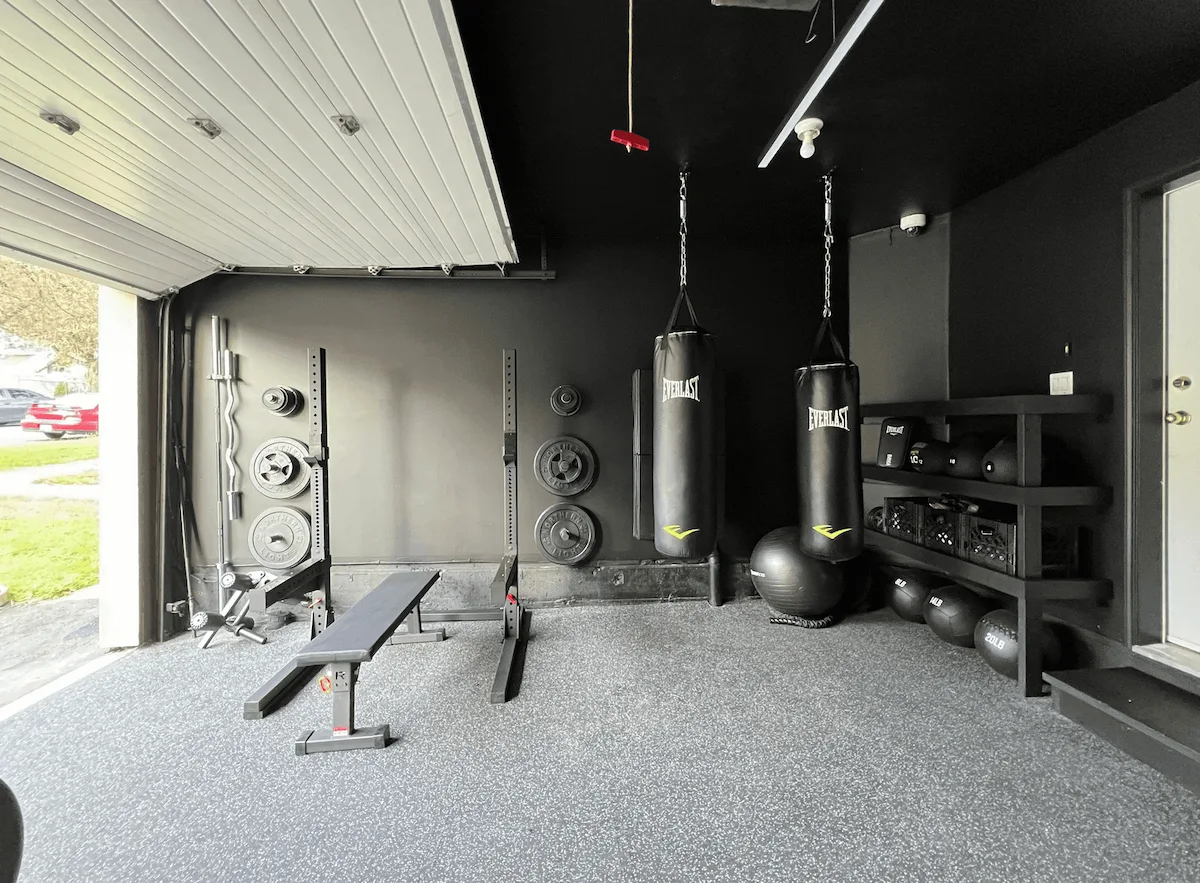 Garage gym build with squat rack, boxing bags, and rubber flooring, part of a fully customised home gym design in Canada.