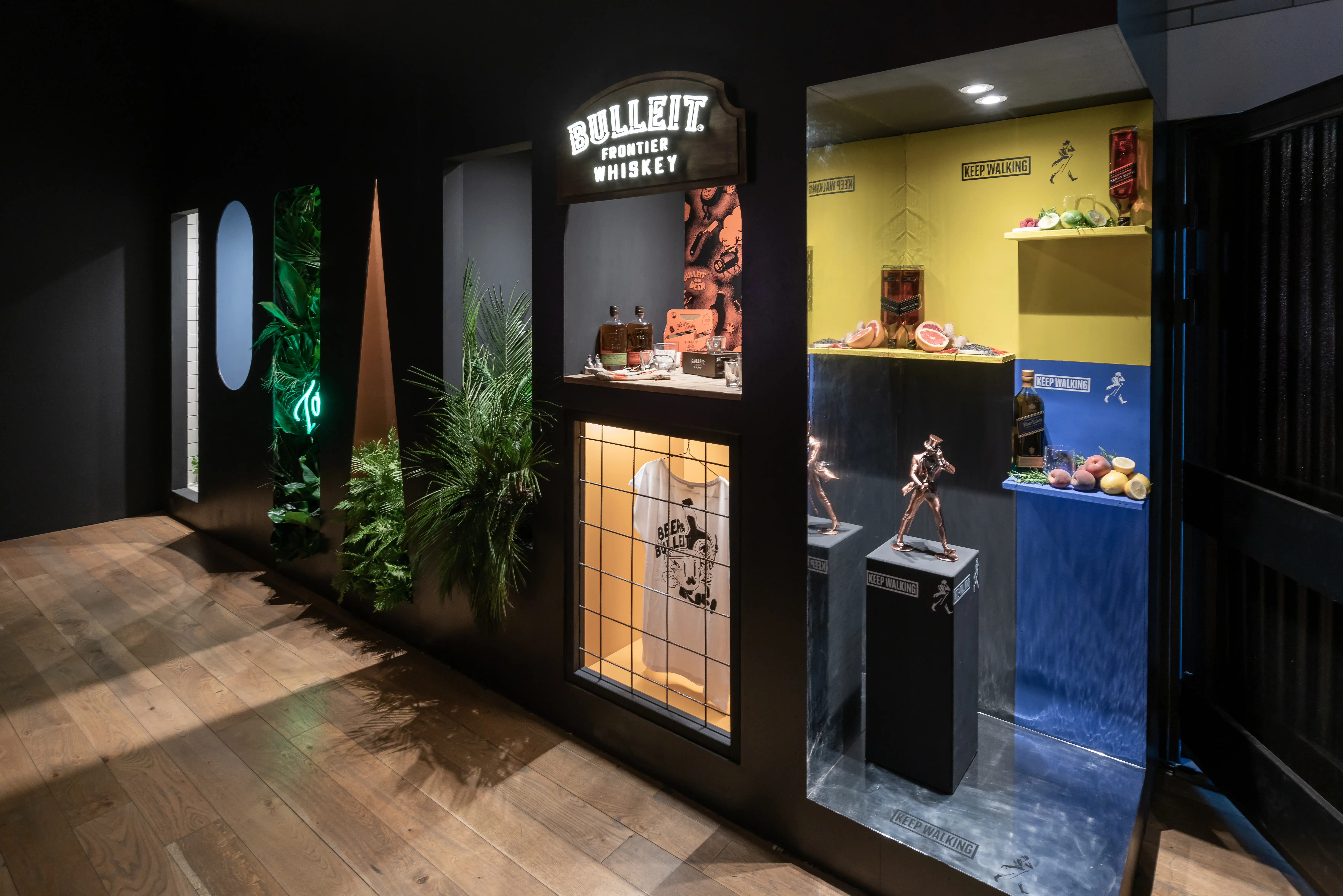 Brand niches at DIAGEO BCB19 with Bulleit Frontier Whiskey sign, copper figures on pedestals and a yellow-blue Johnnie Walker display.