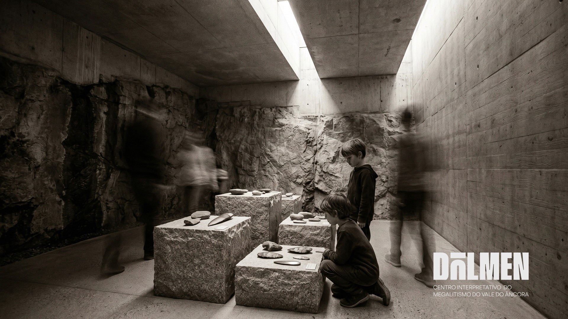 Black and white interior of the Dolmen interpretation centre with children examining stone artefacts on concrete plinths 