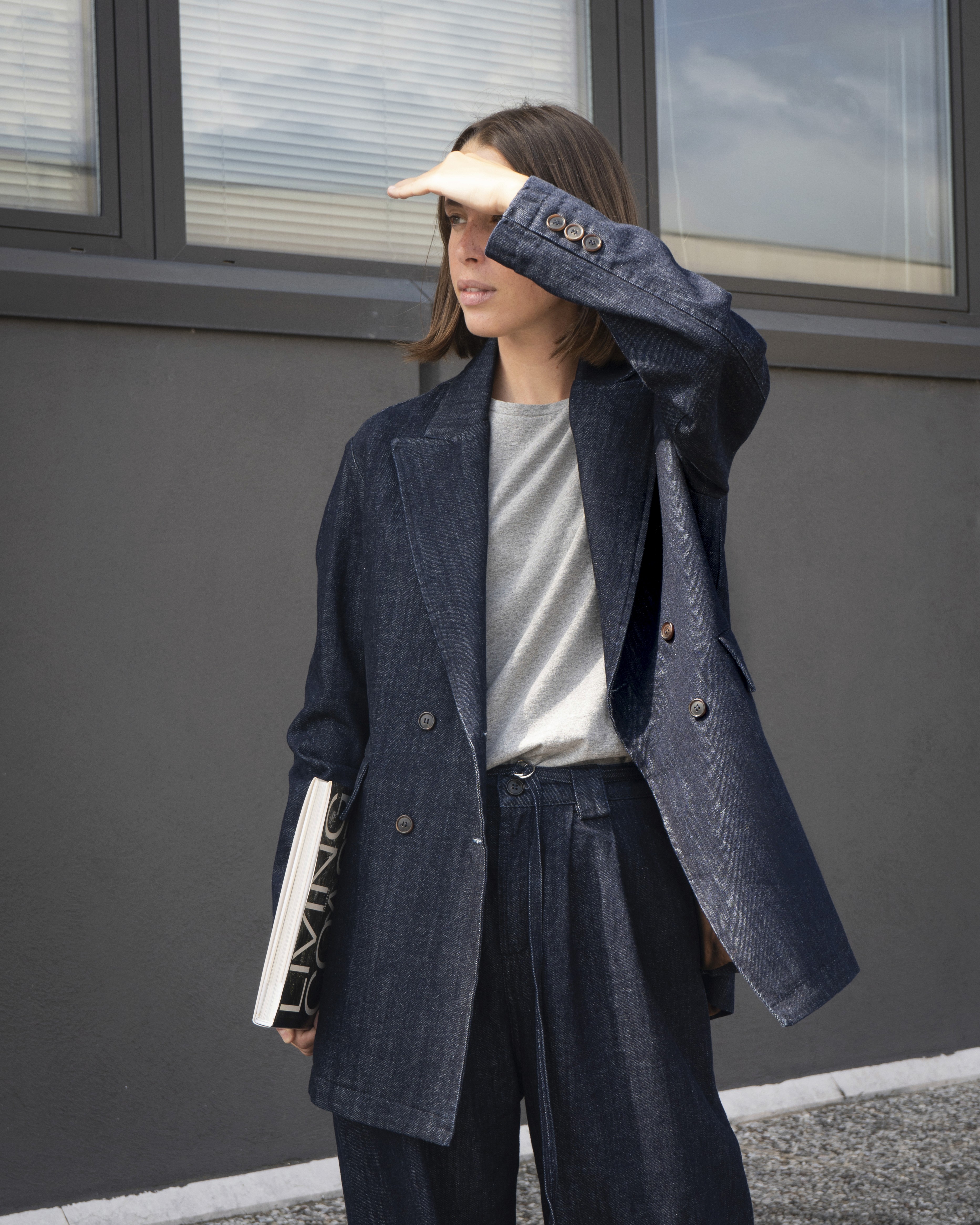 Une femme regarde au loin vêtu d'une blazer en denim dans le lookbook de Paper Wardrobe