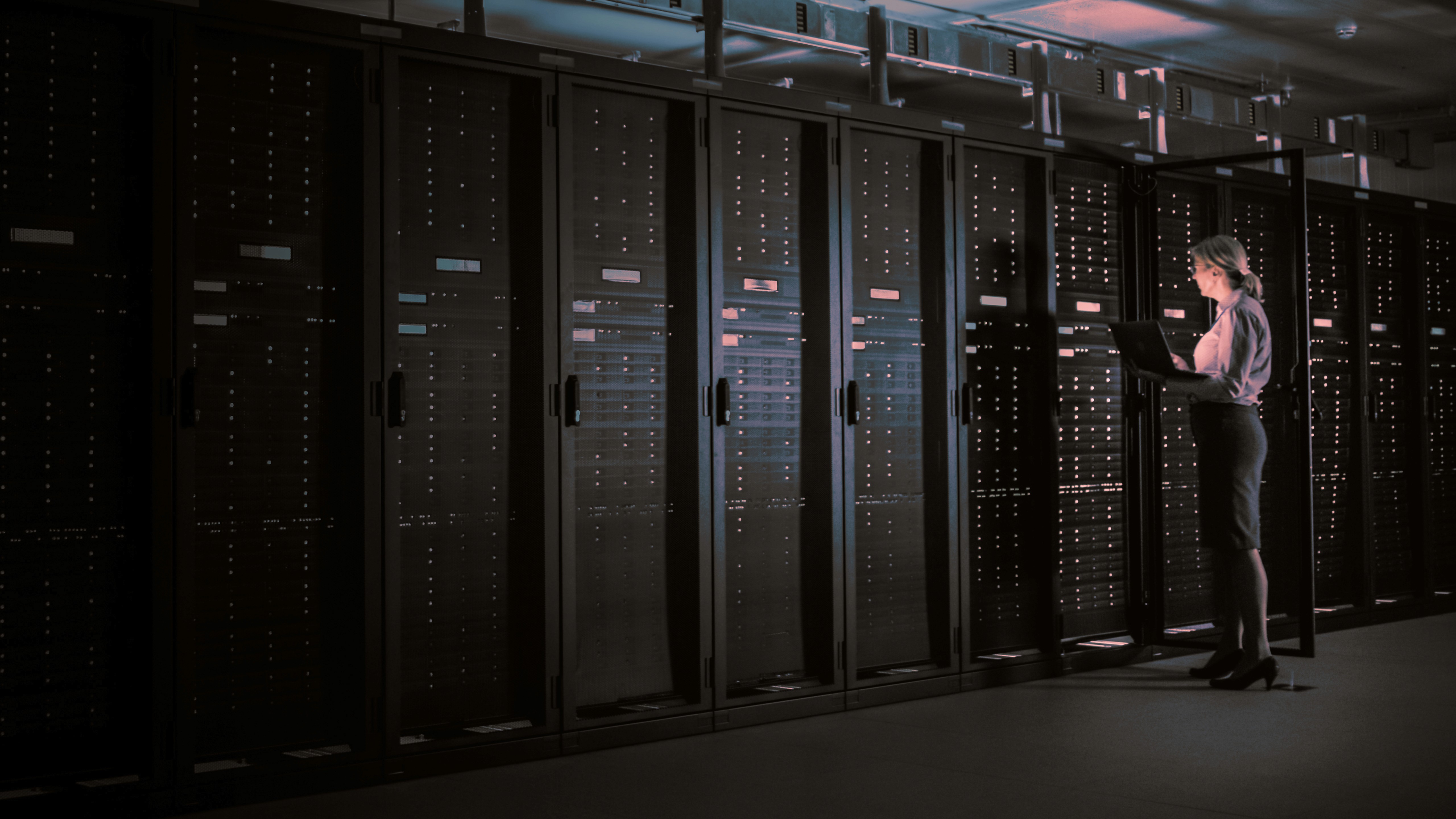 mulher segurando um notebook em um datacenterenquanto mexe em um dos hacks