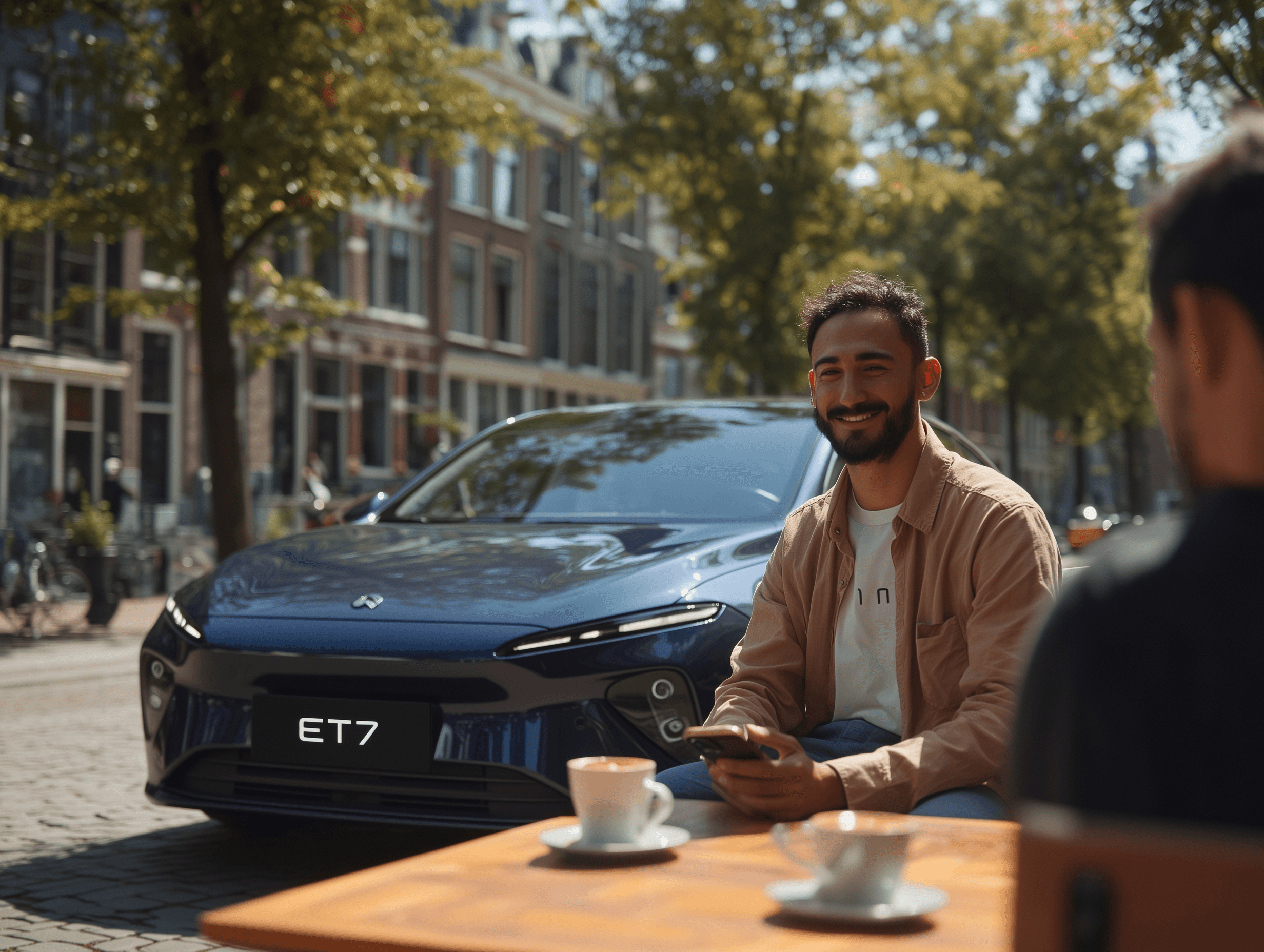 Man smiling at the camera sitting on a terrace with a blue nio et7 behind him