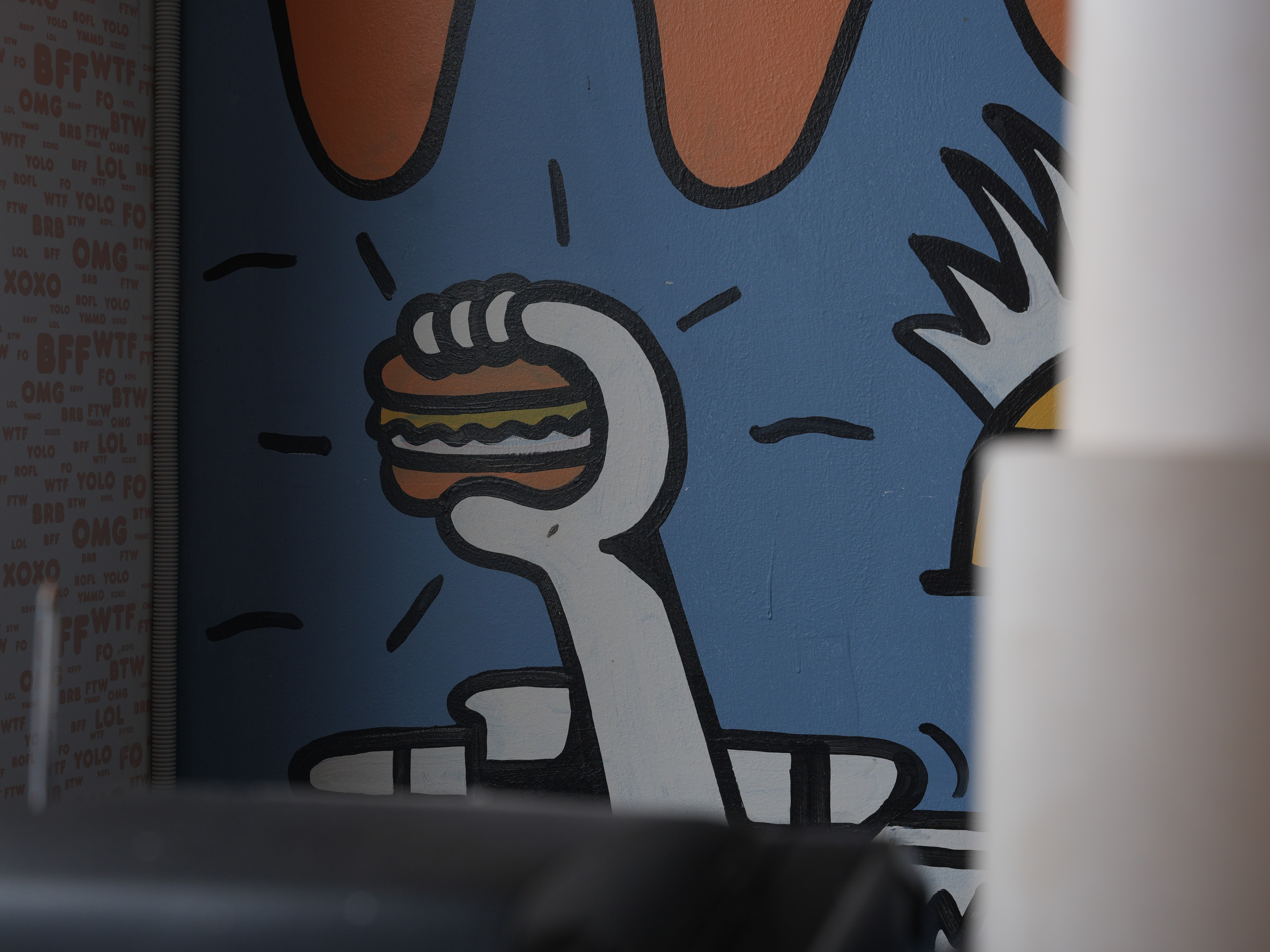 Hospitality fit-out for Heyburg in Coburg, Victoria with neon Hey'Burg signage, terrazzo counter, custom pop-art murals, brass pedestal tables, pendant lighting.