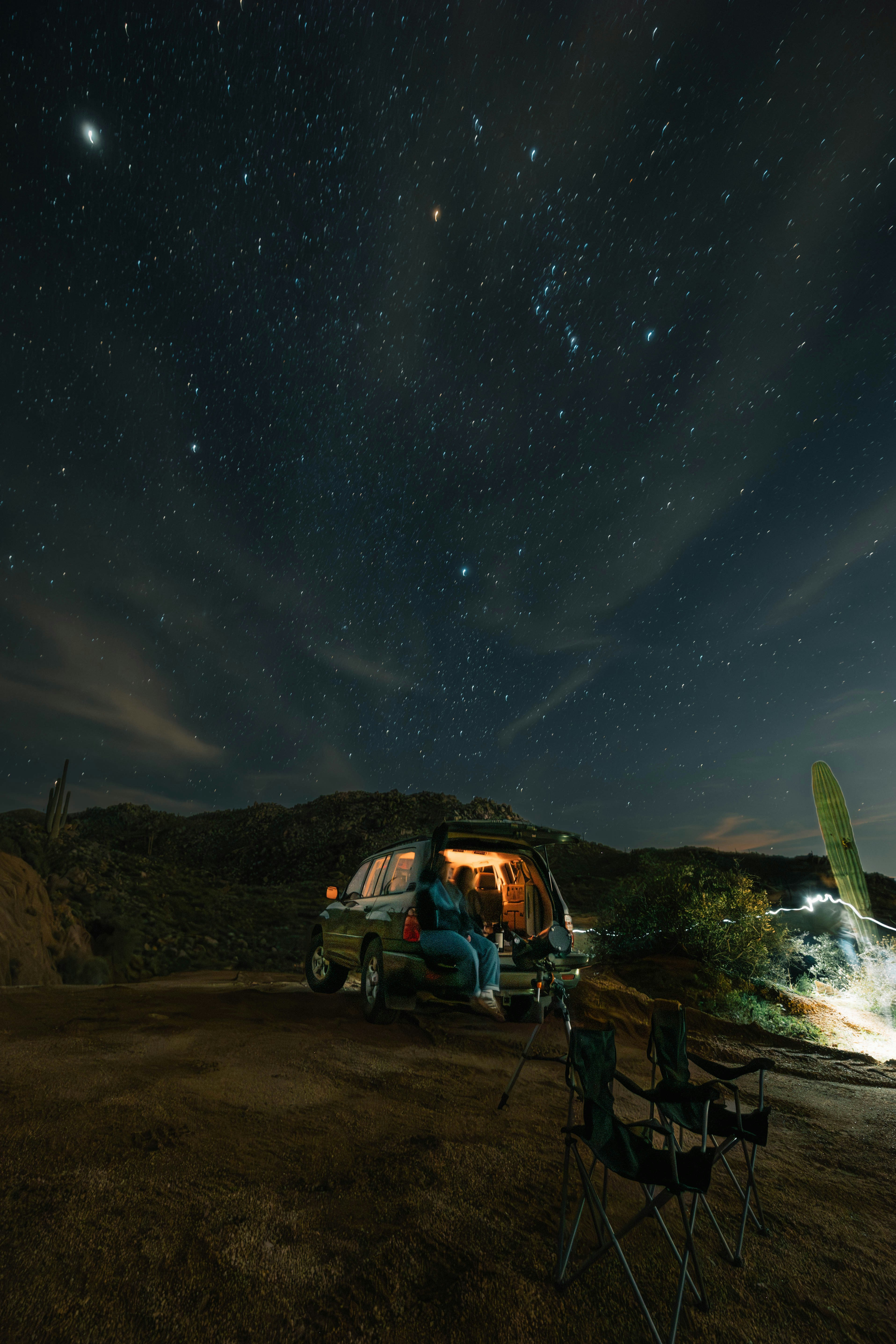Couple stargazing from car under starry night sky