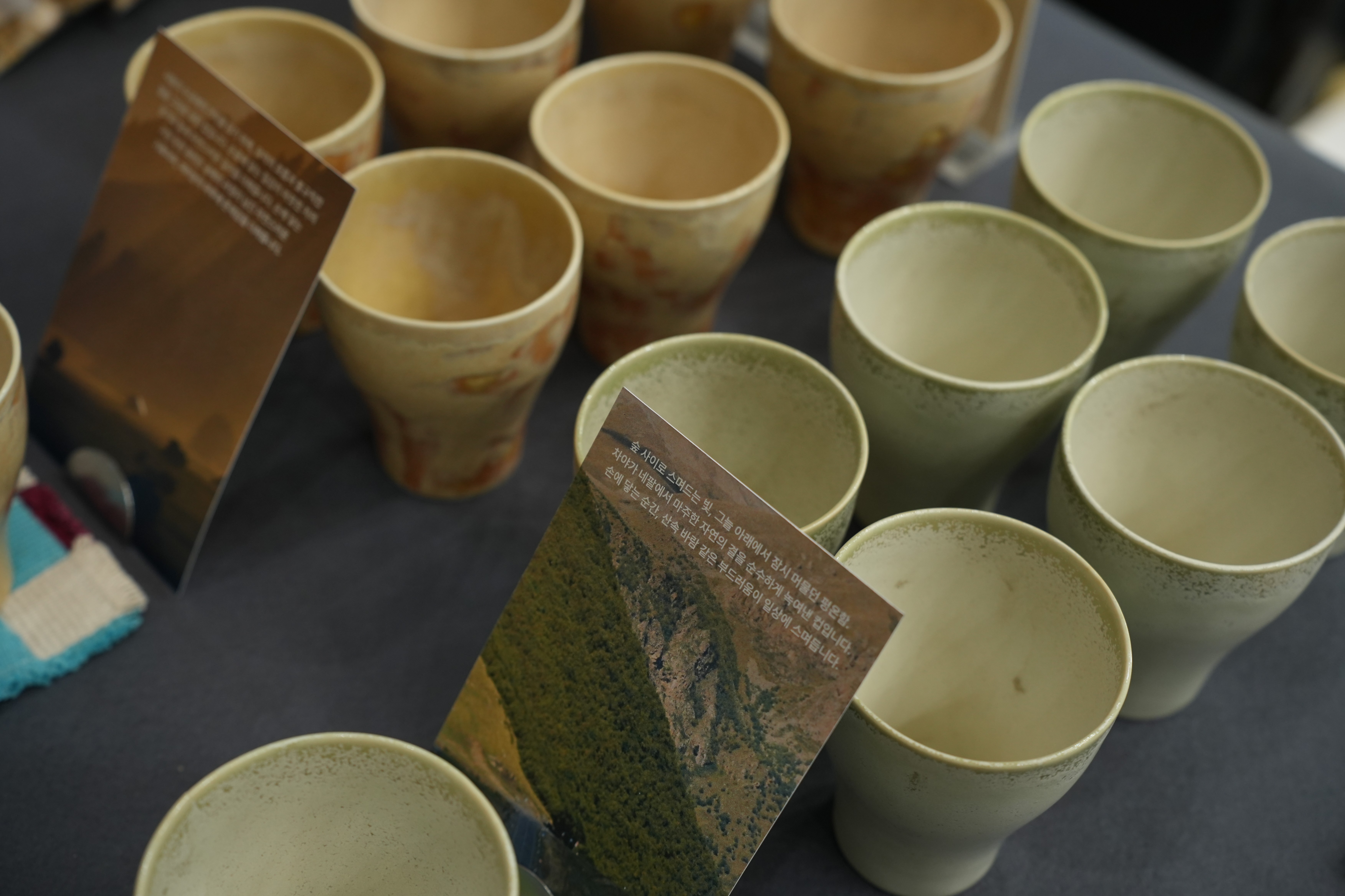 Person with a mustache wearing a black t-shirt carrying a tall stack of pizza boxes inside a dimly lit bar or restaurant.