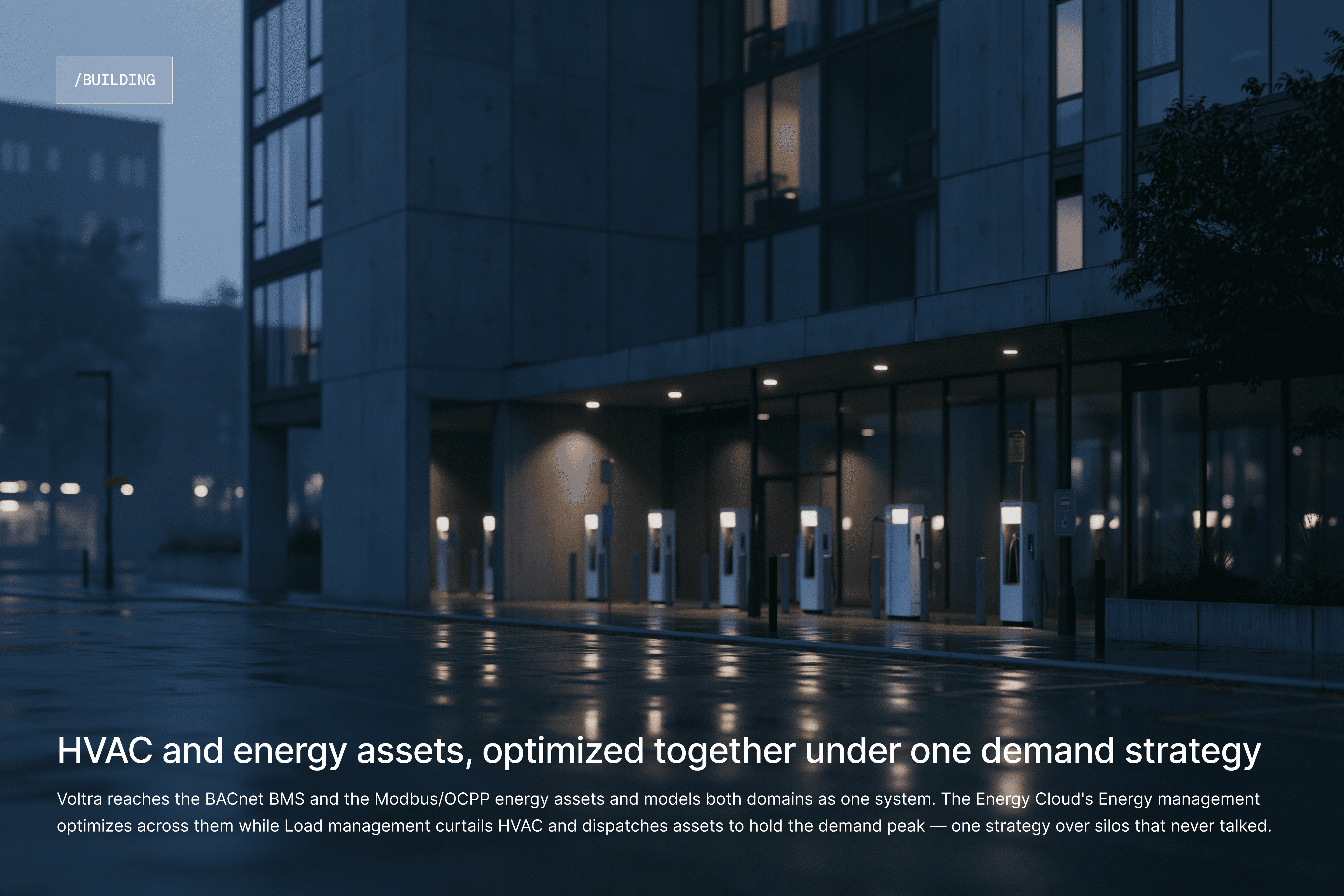 Modern commercial building exterior at night with EV chargers out front.