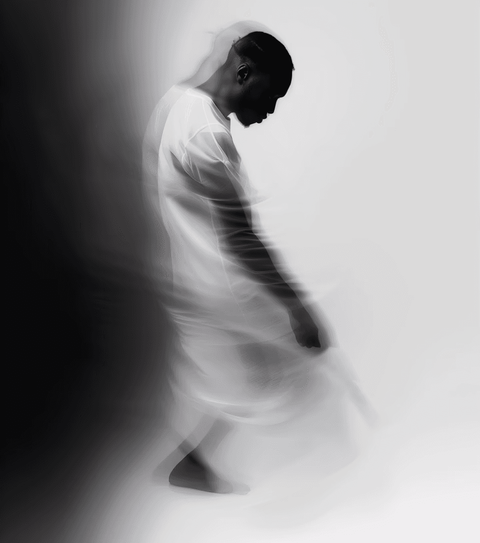 A blurred, ethereal image of a person in white, facing right, with a bowed head. The soft focus and motion convey a contemplative, serene mood.