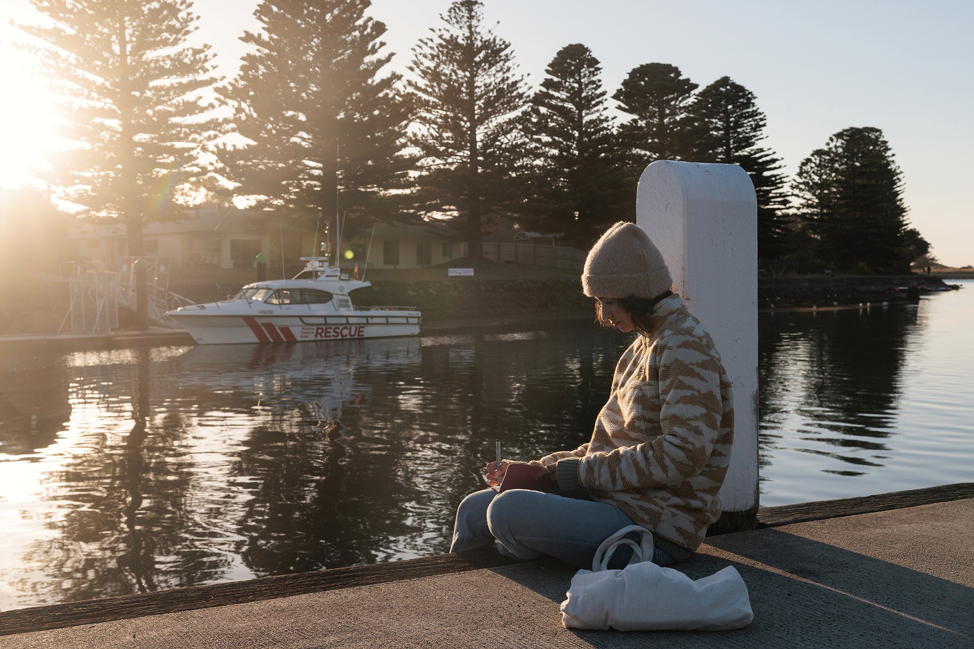 Woman writing in a journal on a wharf