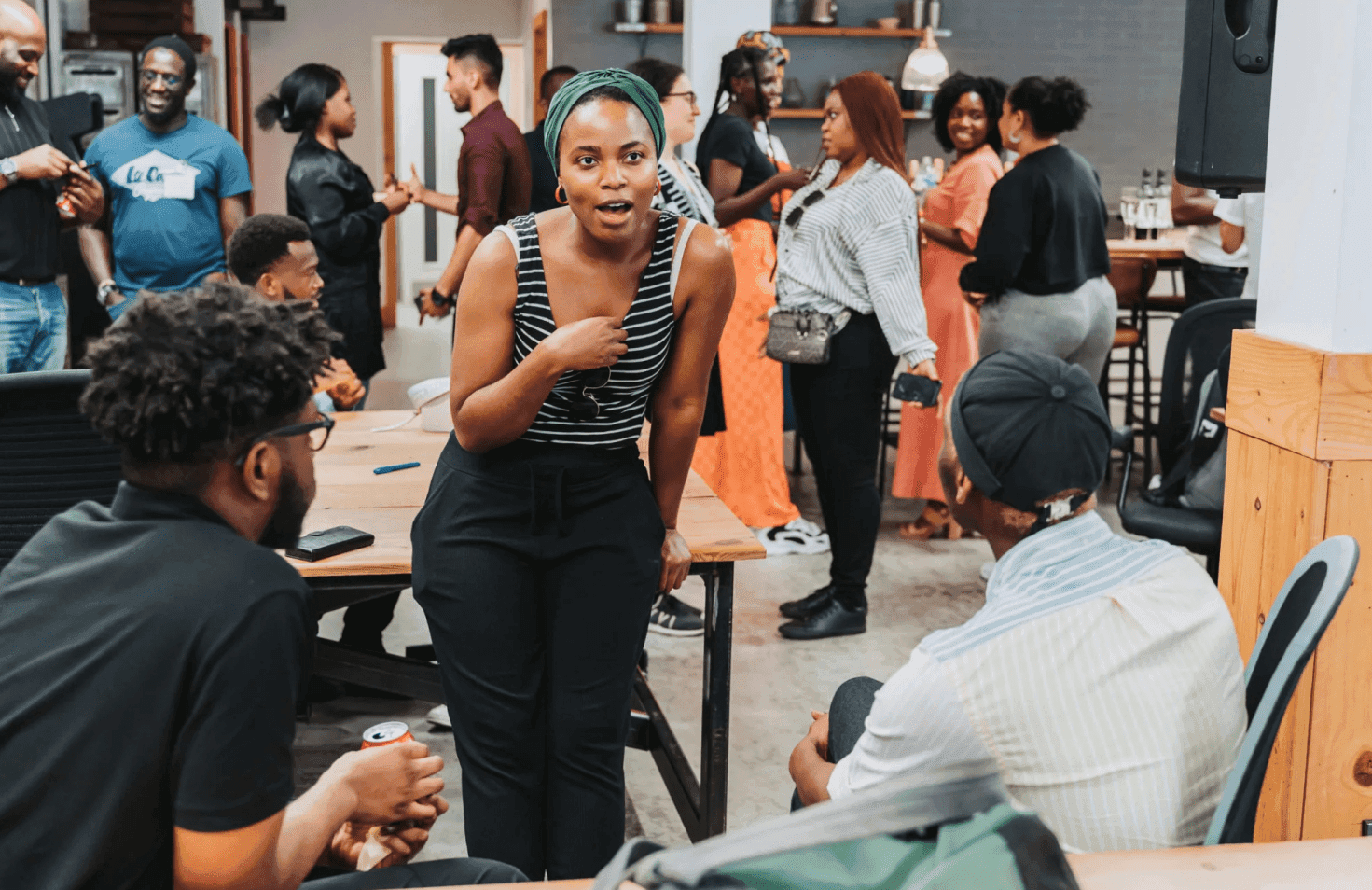 People talking and others standing around a table outdoors.