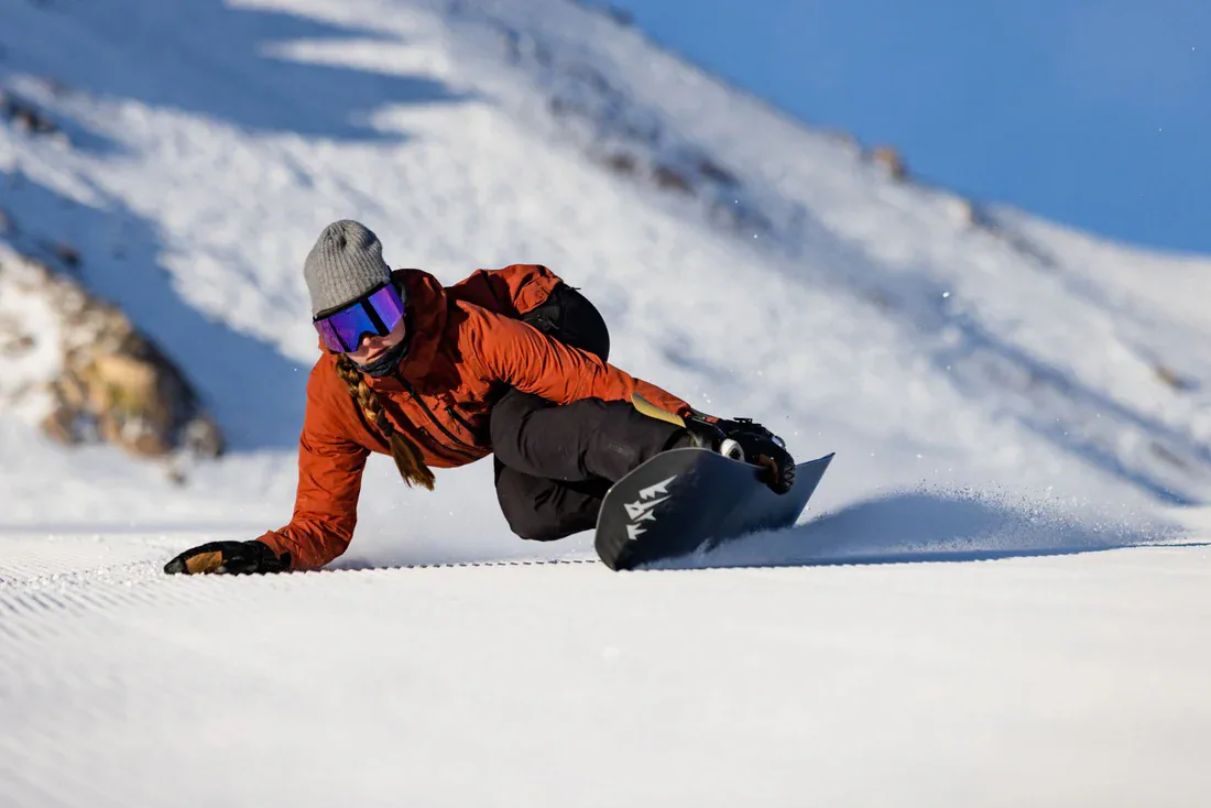 Female snowboard carver making a tight turn with lots of edge angle.
