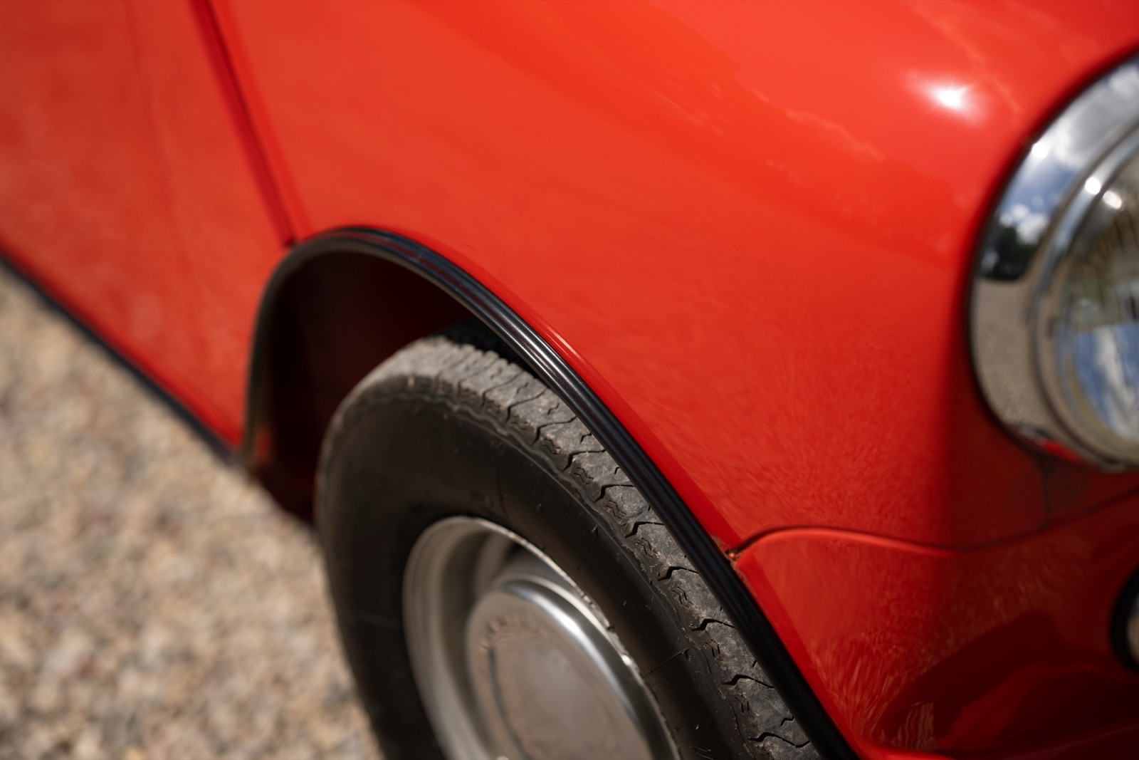 Close-up of a bright red car's wheel and fender, showcasing the tire and shiny detail of the bodywork.