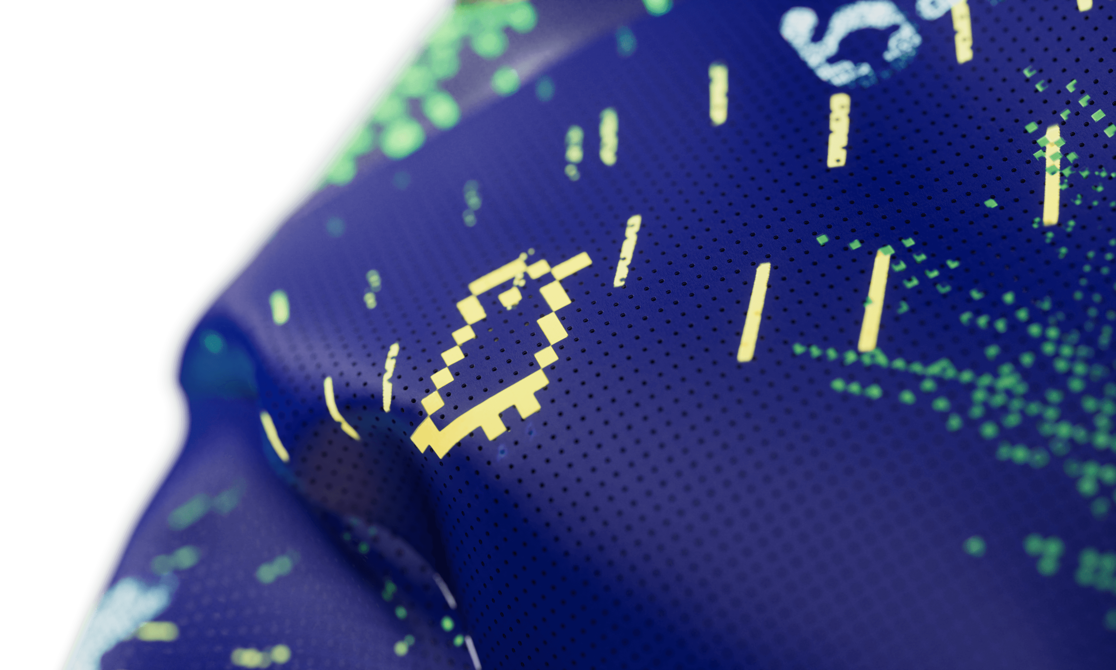 Extreme close up of the navy blue jersey fabric showing a pixelated yellow smiley face graphic and green dot pattern printed on a perforated textile surface